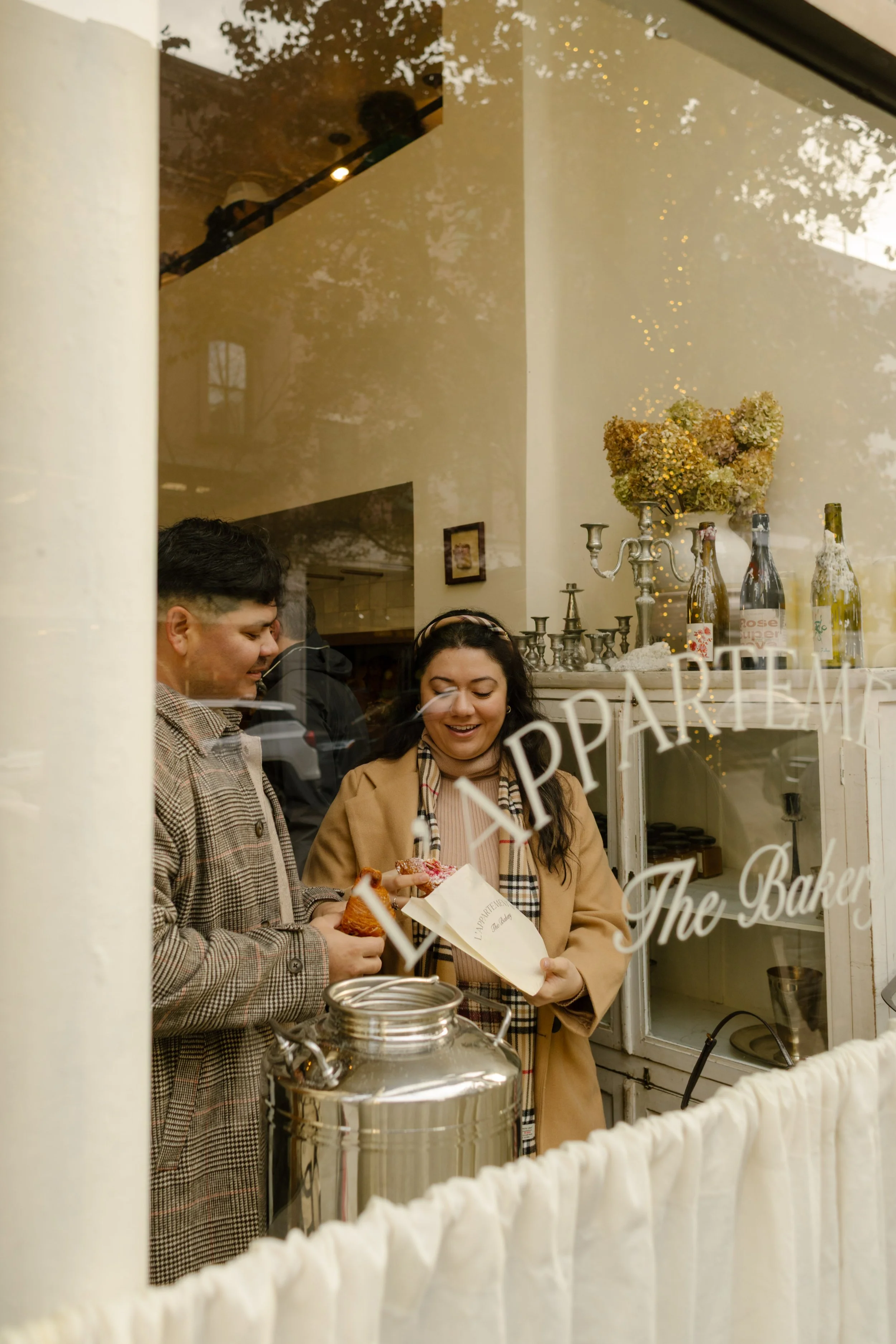 Brooklyn engagement photos of a couple picking out pastries together through the window of a neighborhood bakery.