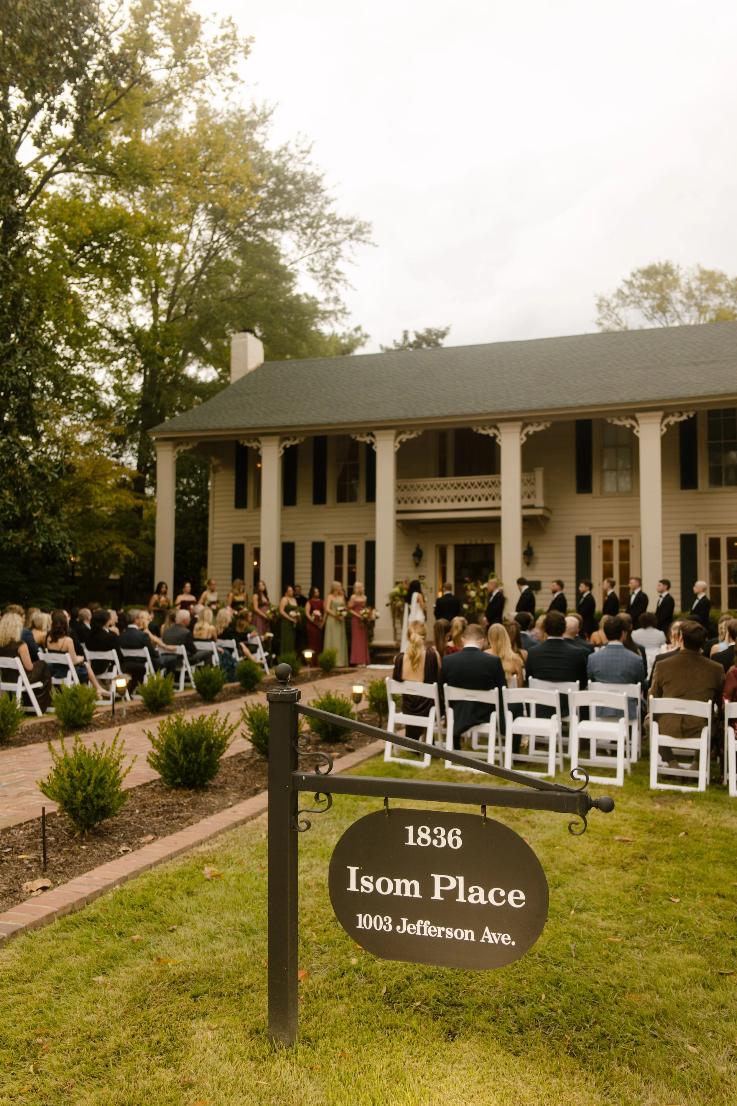 Outdoor wedding ceremony at Isom Place featuring bridesmaids in moody wedding colors of burgundy and olive green.