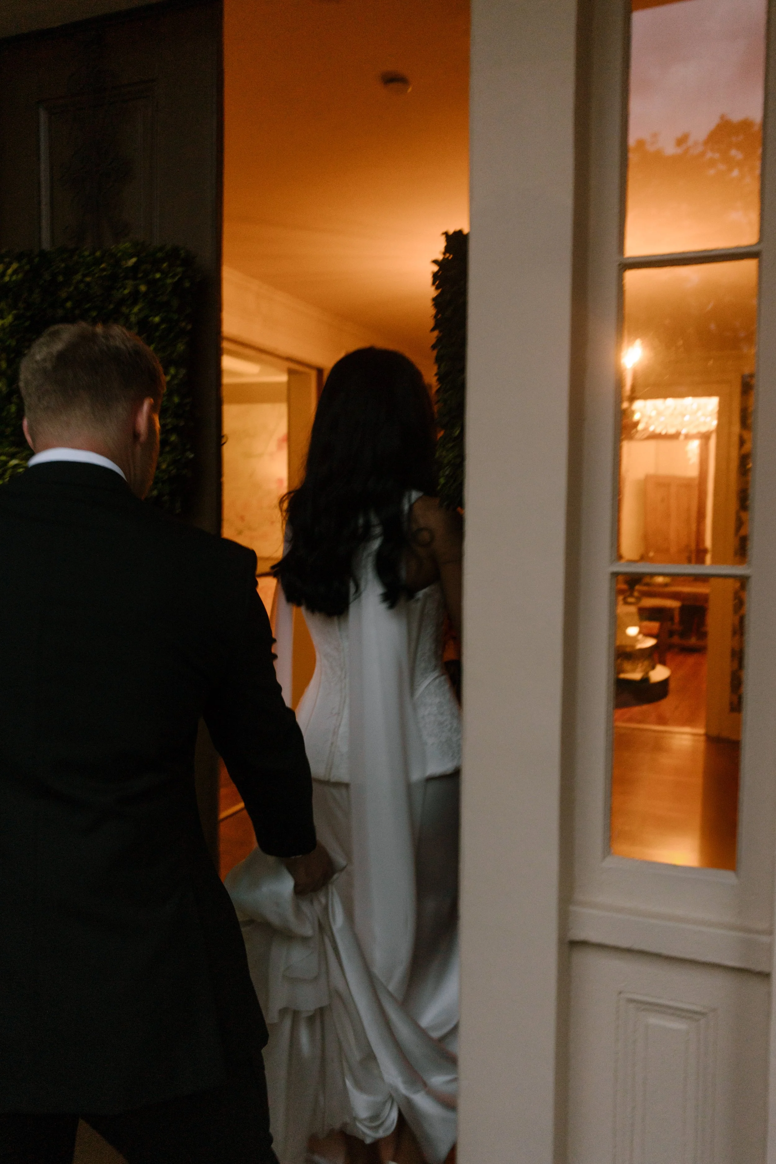 Bride and groom entering a warmly lit historic wedding venue, with moody wedding colors creating a romantic evening atmosphere.