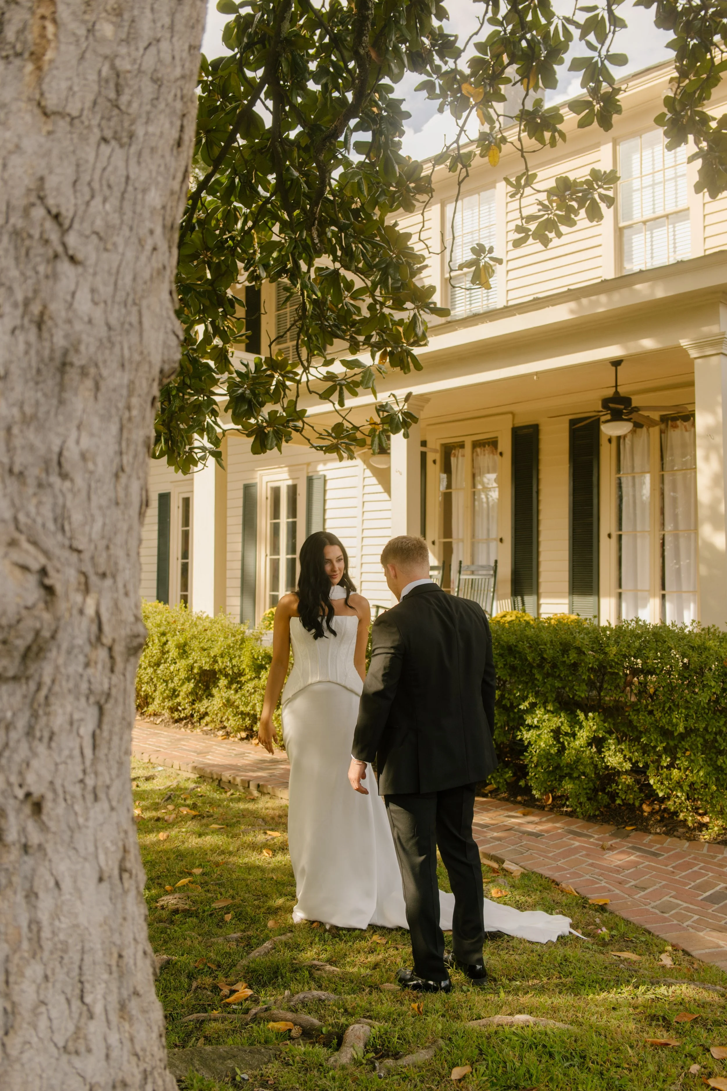 Bride and groom sharing a quiet outdoor moment beneath the trees beside their historic wedding venue.