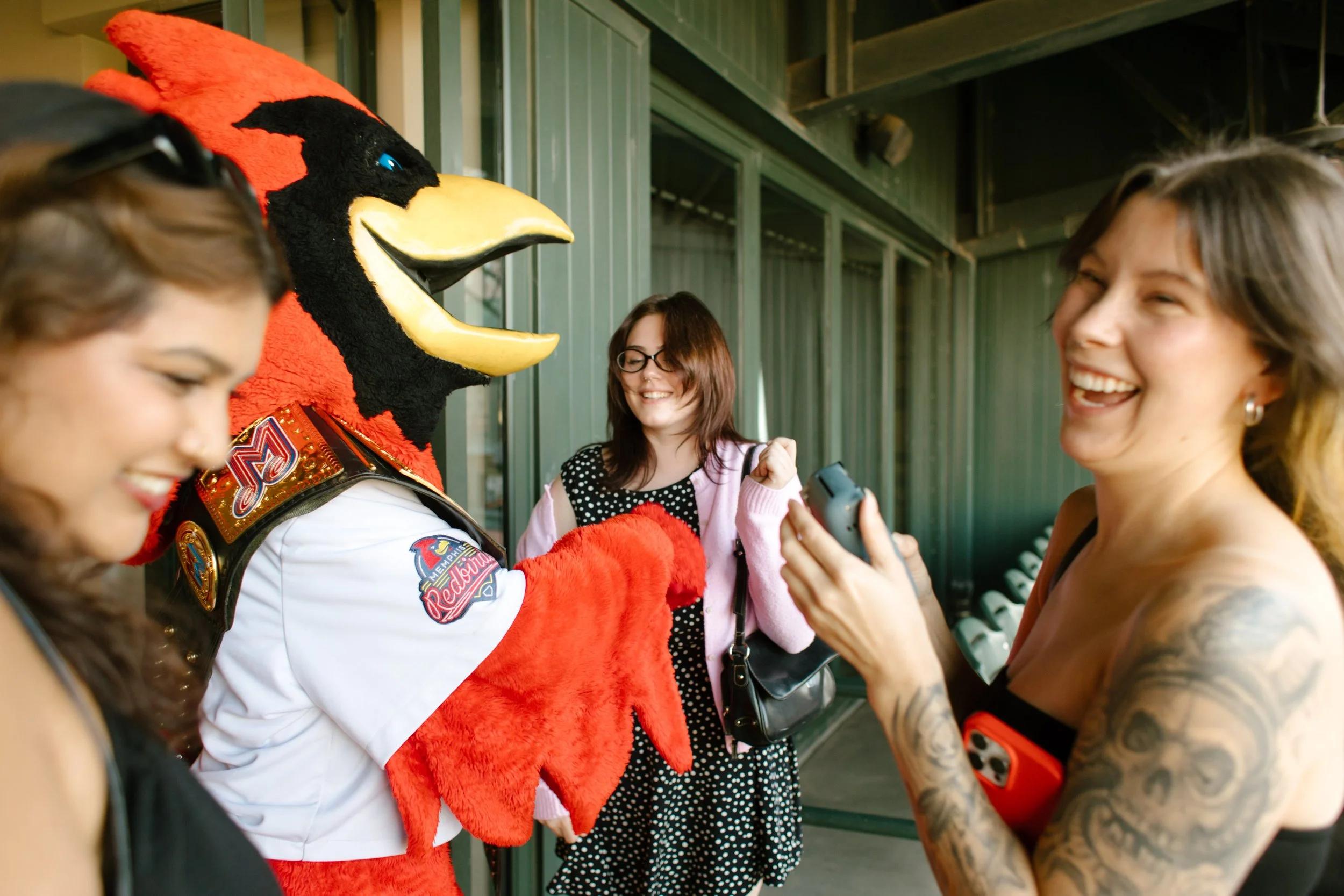 A baseball mascot interacts with laughing guests on a stadium concourse, capturing the playful energy that inspires fun engagement photos.