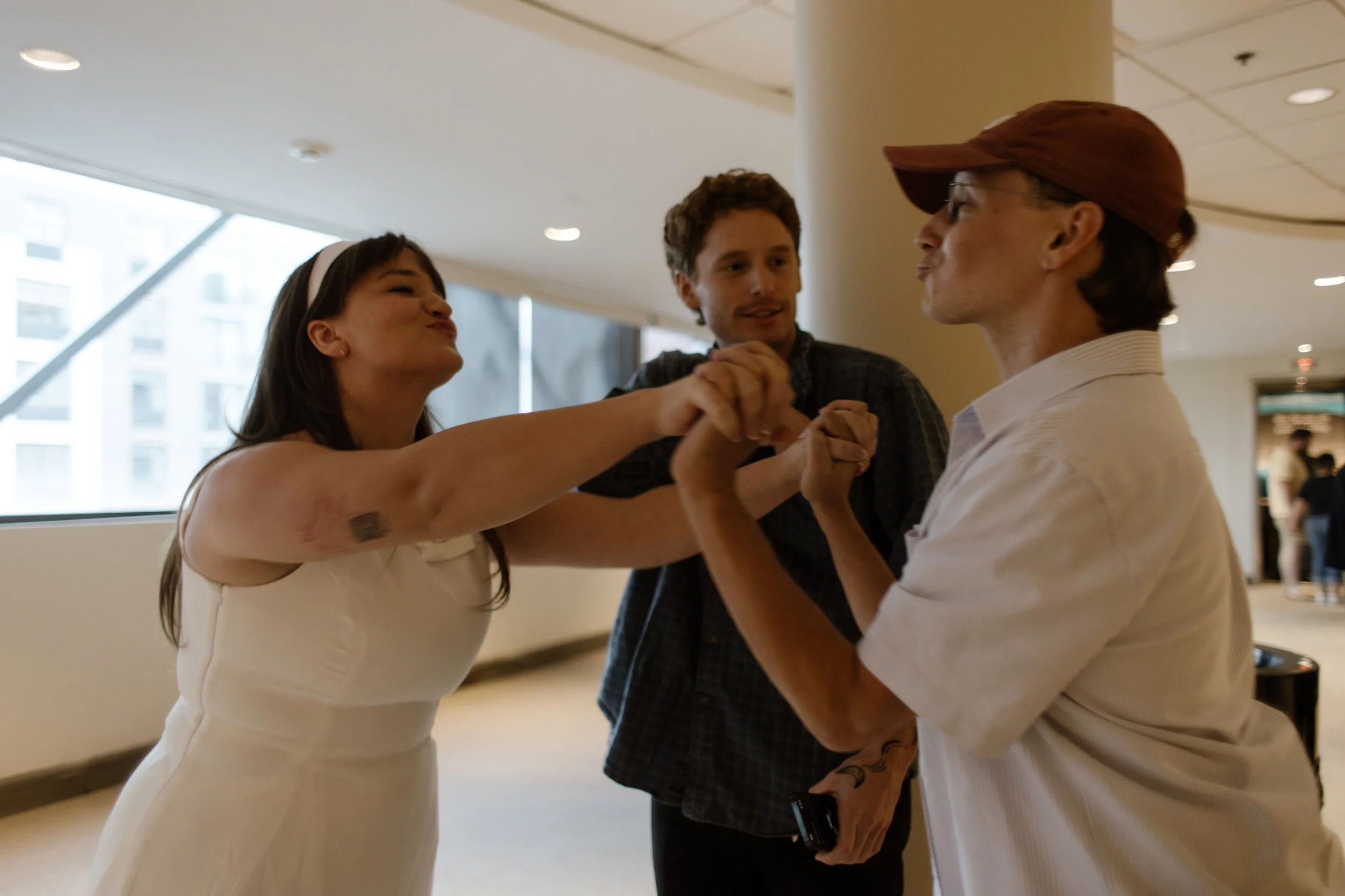 A couple playfully fist-bumps in a stadium hallway during their baseball-themed wedding rehearsal celebration.