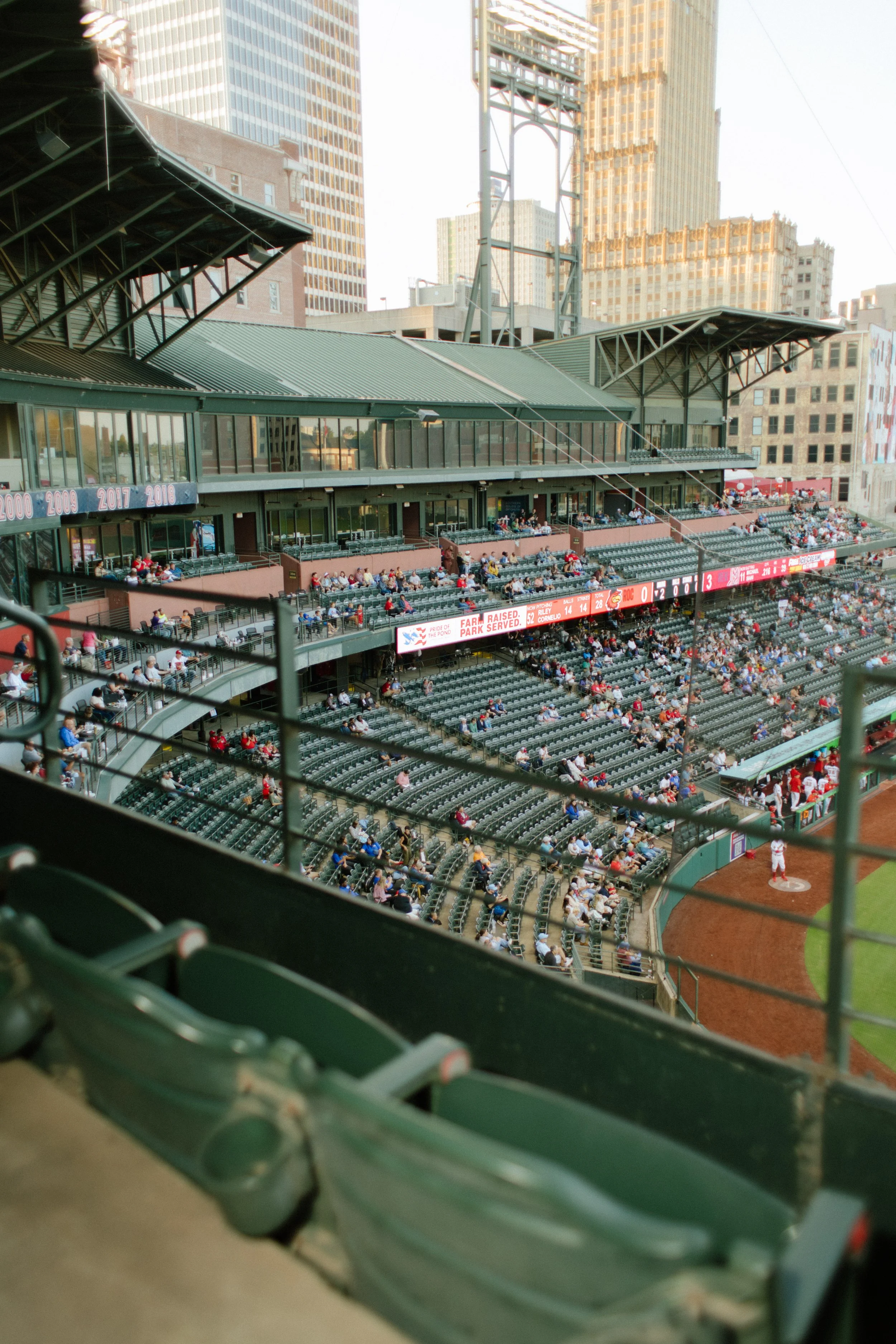Empty green stadium seats overlooking the baseball field and surrounding city buildings, a playful setting for fun engagement photos inspiration.
