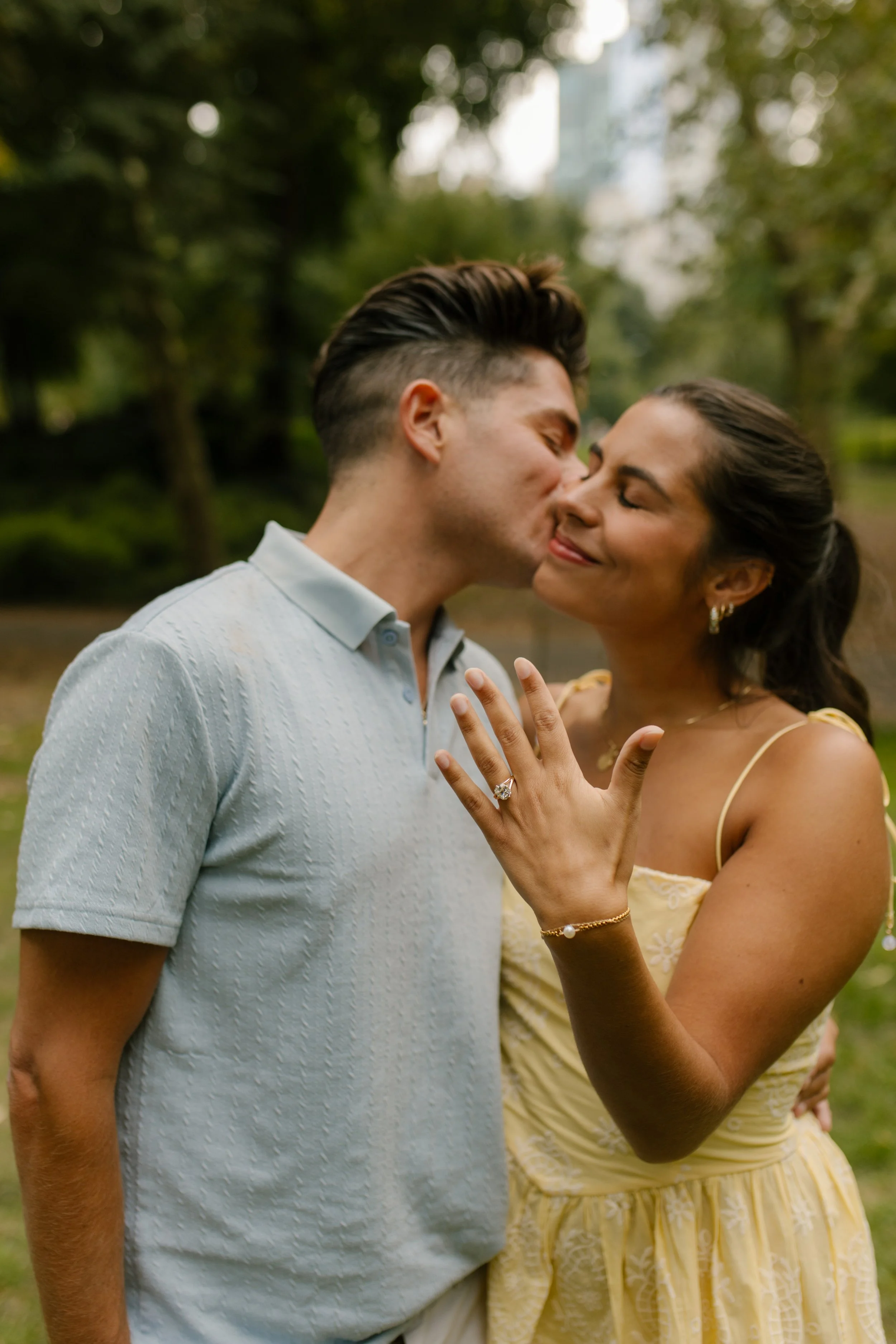 Chris kisses Sienna on the cheek as she smiles and shows off her engagement ring following their romantic new york proposal in Central Park.