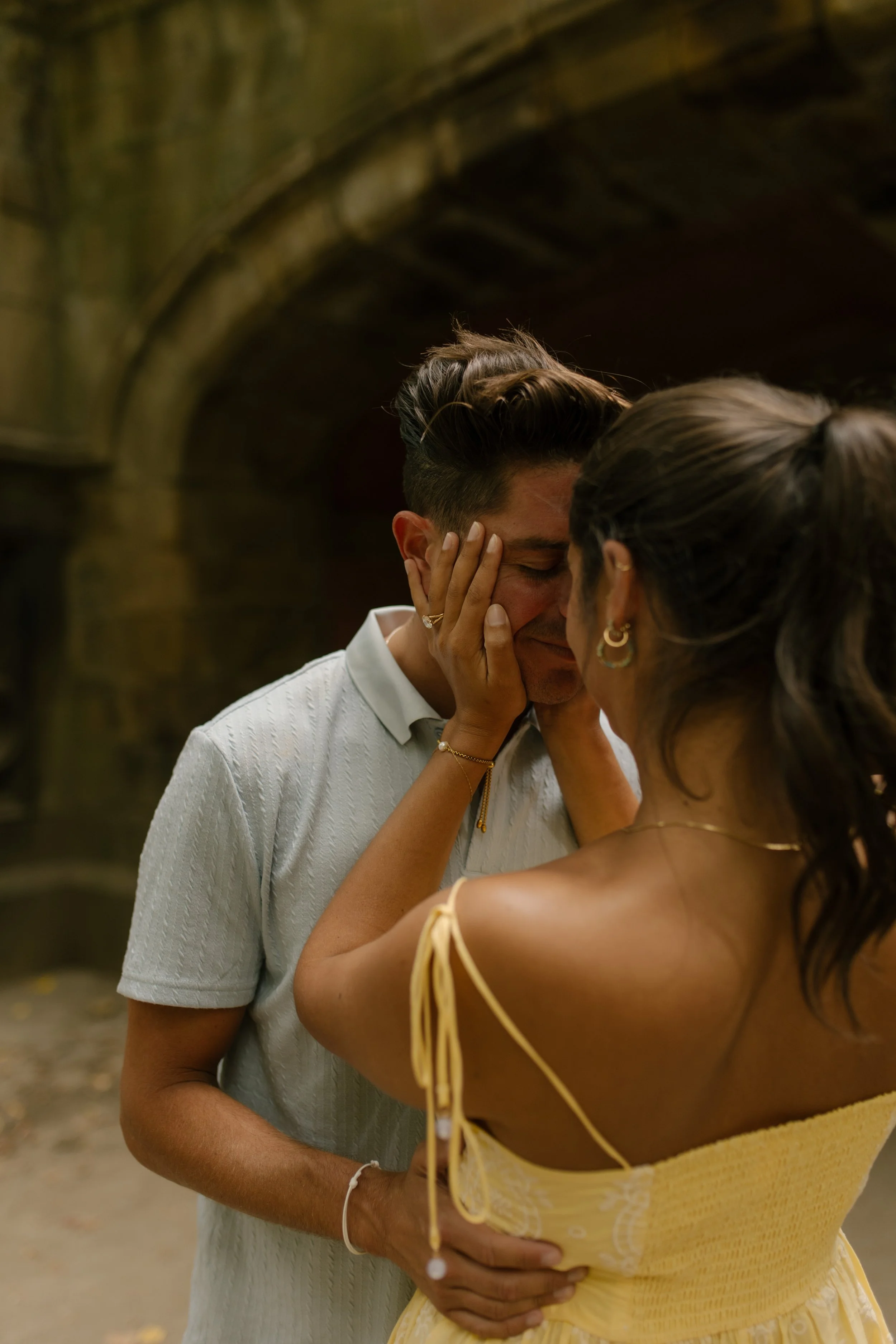 Sienna gently holds Chris's face as they share an intimate moment beneath a stone archway in Central Park.