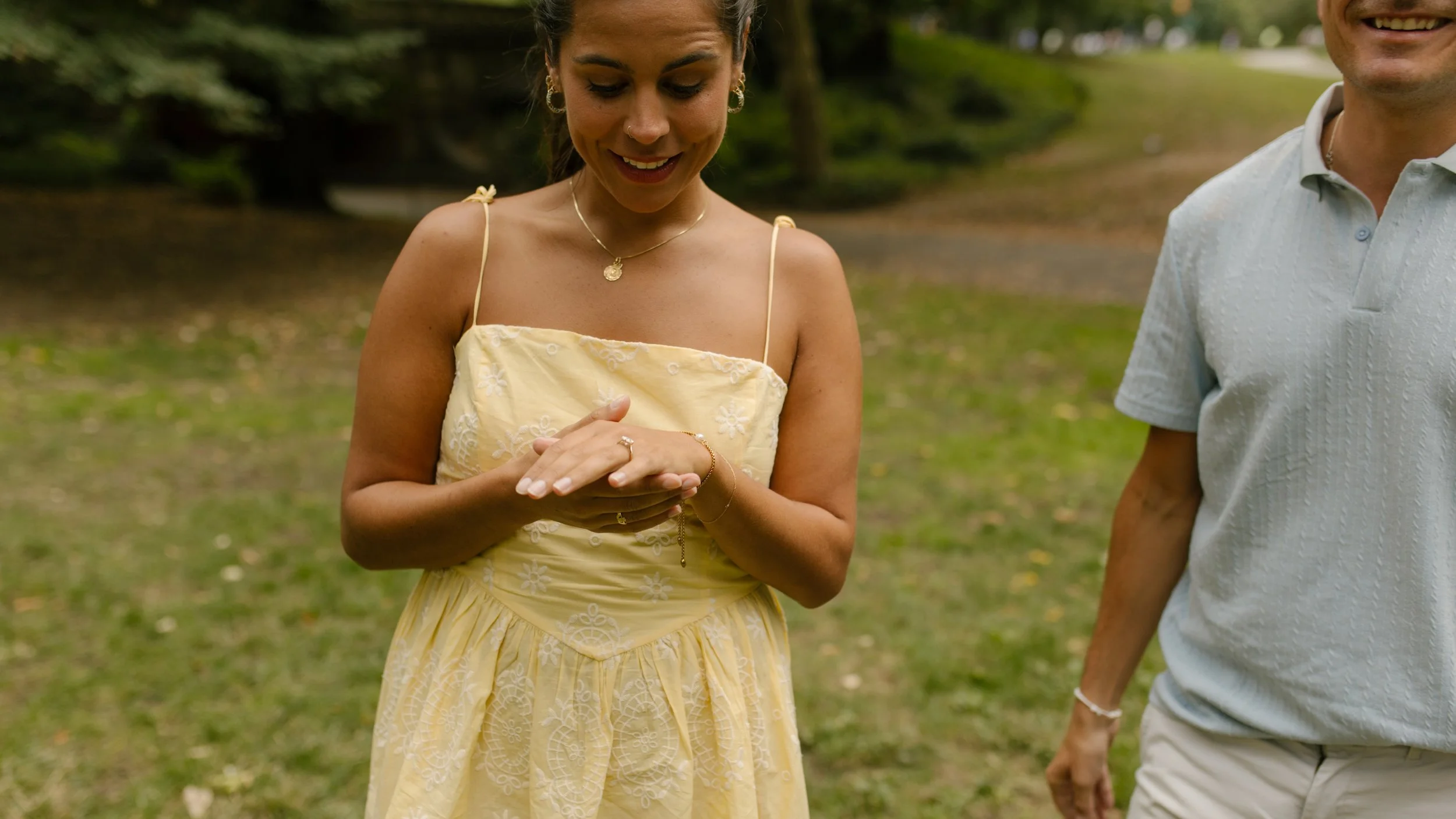 Cropped photograph of Chris and Sienna holding hands against an ornate Central Park stone railing, showing their outfits and fallen leaves along the pathway.