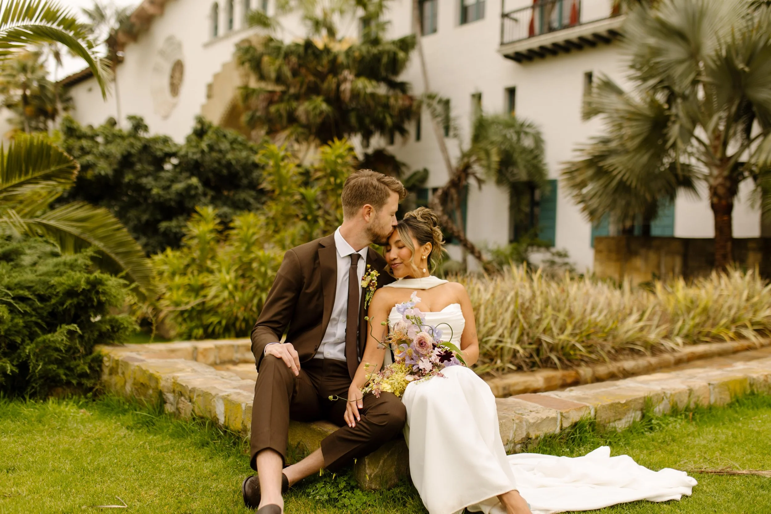 They sit in the grass outside the courthouse, foreheads pressed together after their wedding Santa Barbara Courthouse ceremony.
