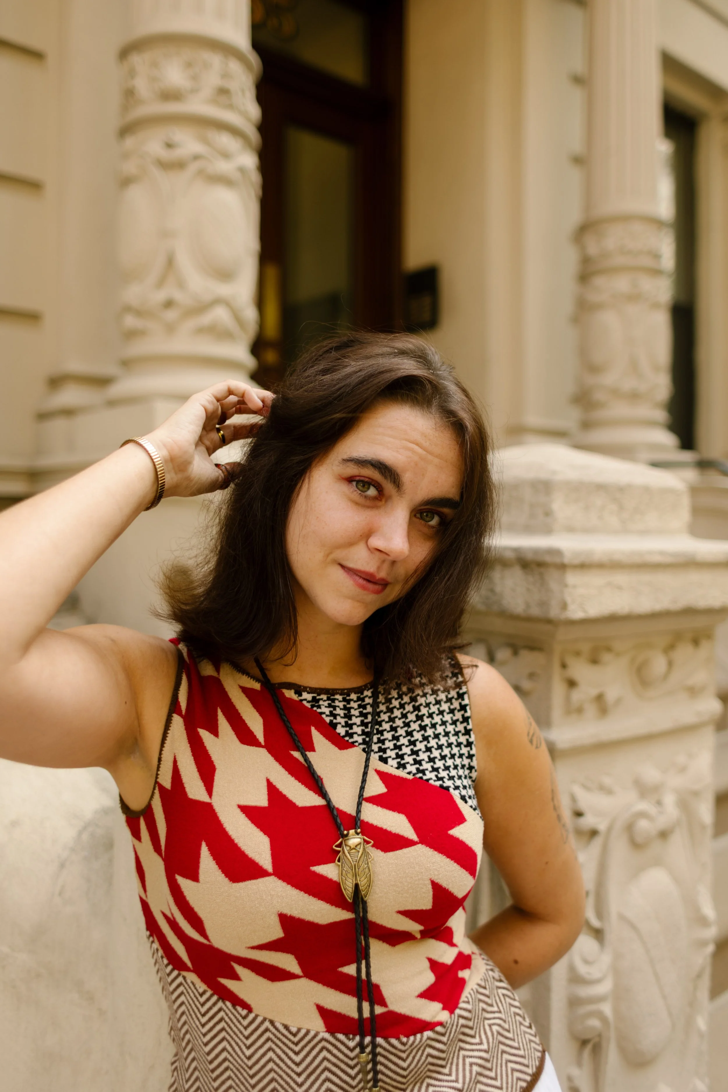 Portrait of a woman posing in front of ornate architectural columns during a city lifestyle photography session.