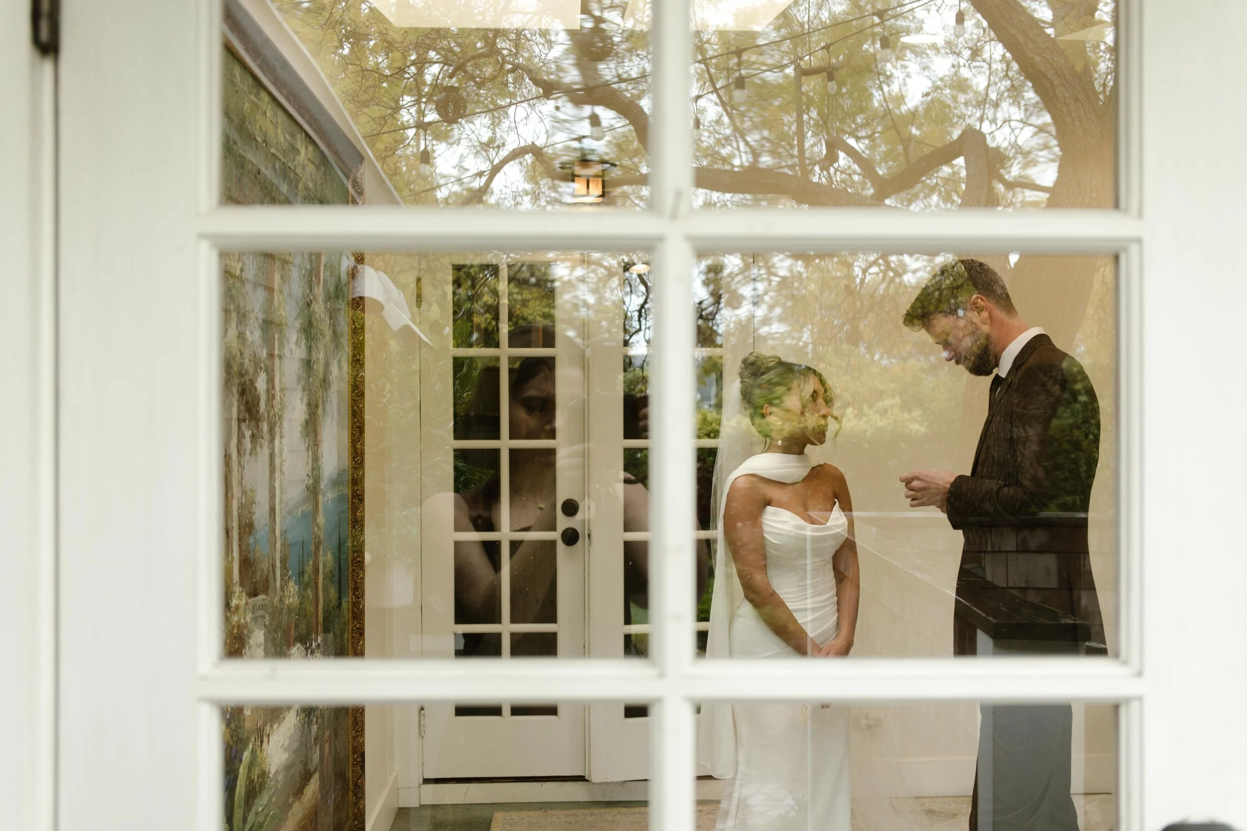 Through a window, the couple shares their vows in a private first look before their wedding Santa Barbara Courthouse ceremony.
