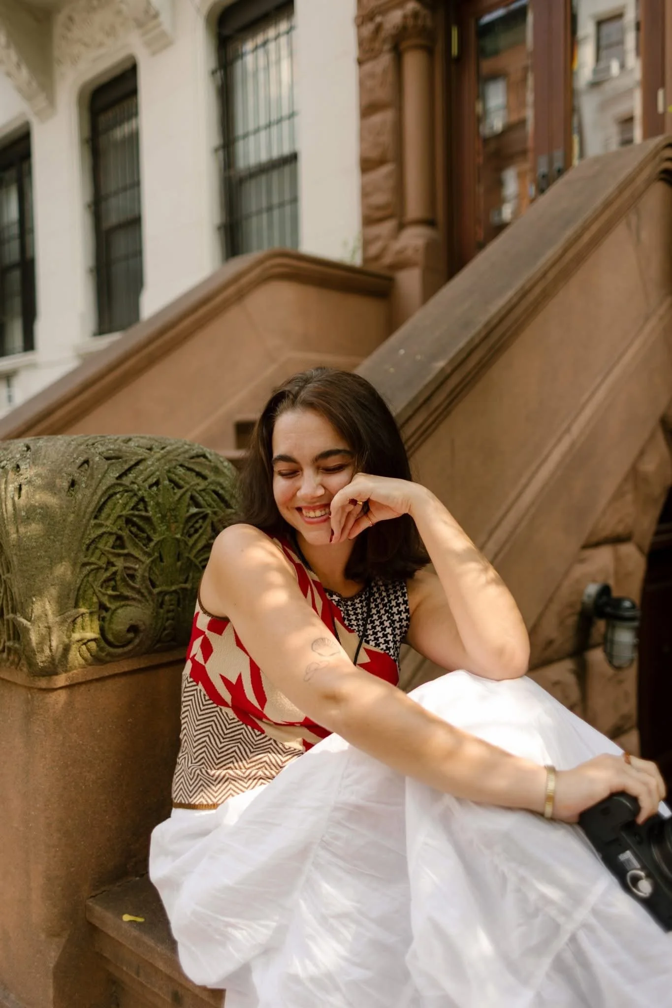 New York City courthouse wedding outfit with a colorful patterned top and full white skirt photographed on brownstone steps