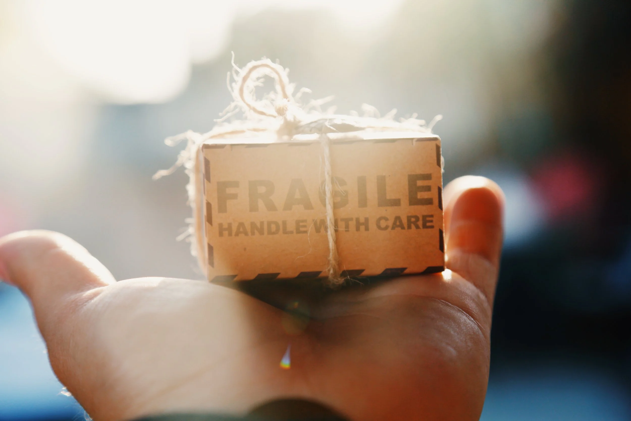 Image shows a hand with a small brown box that reads ‘fragile - handle with care’ to highlight the care and commitment Hygge Me places on providing beautifully packaged items.