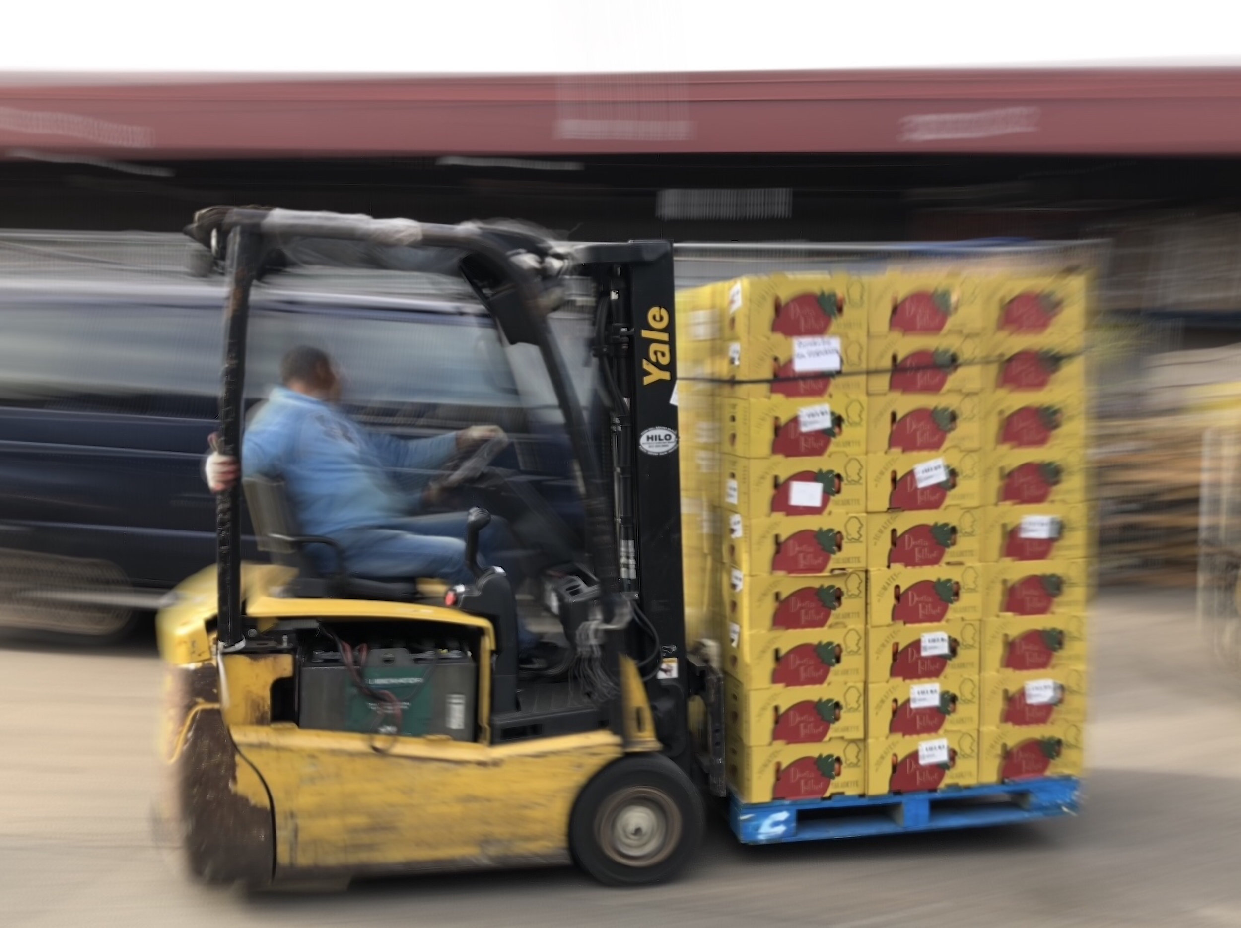 A market employee uses a forklift to move a pallet of tomatoes from the back of a tractor-trailer. The market is a major wholesaler of produce for stores and restaurants across the city.