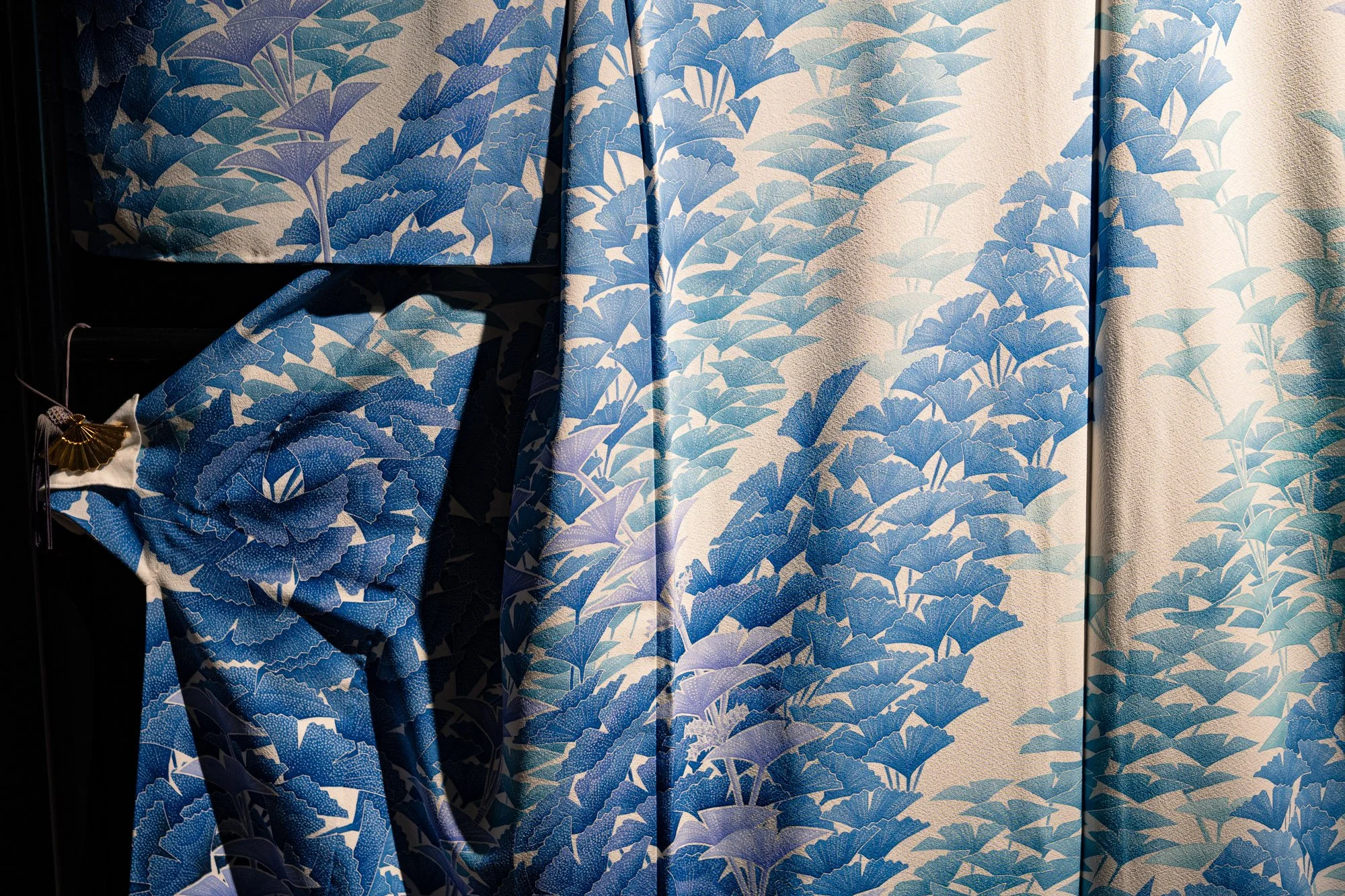 A close up of a silk kimono decorated with blue ginkgo leaves