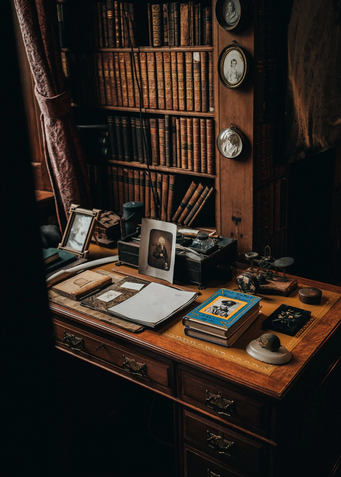 vintage objects and books places on an old wooden desk, backdropped by books