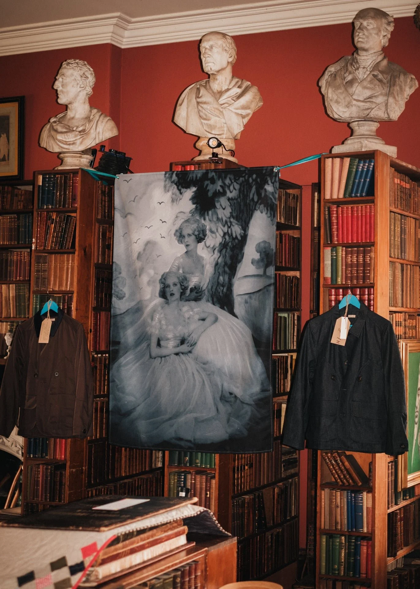 Cecil Beaton hand against an antique bookcase dated over by a collection of classic busts