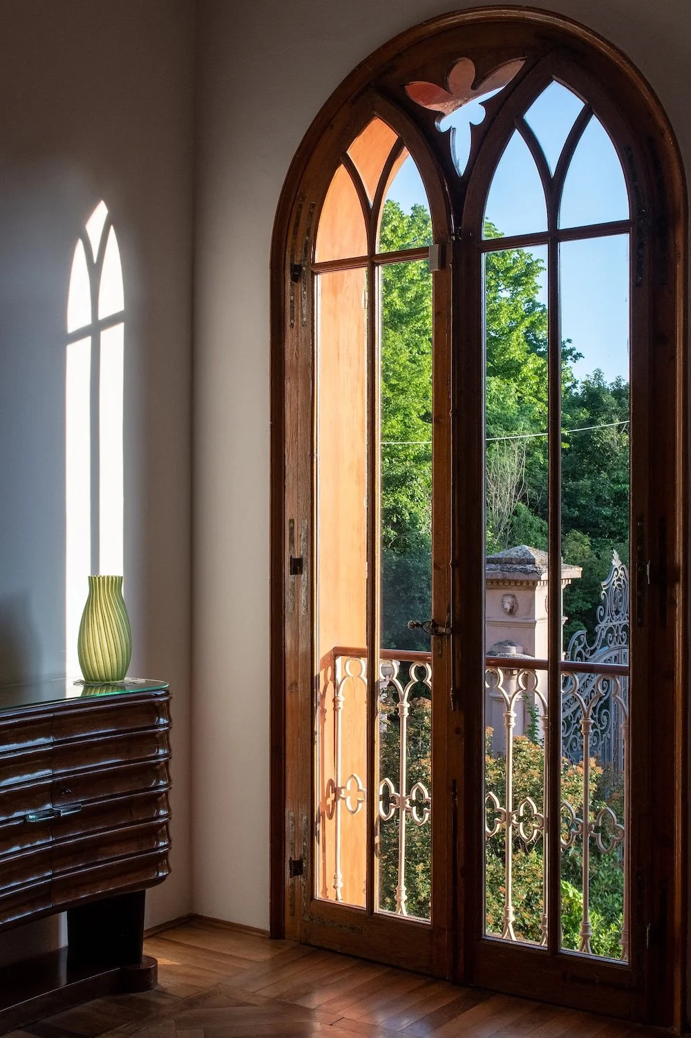 Sunlight streams in through an arched wooden window frame to cast shadows on the tiled floor of  Il Borgo del Balsamico, a guest house in Emilia-Romagna