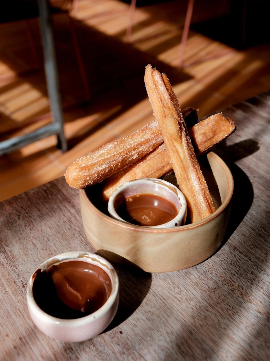 A close up of freshly-made churros, with chocolate dipping sauce