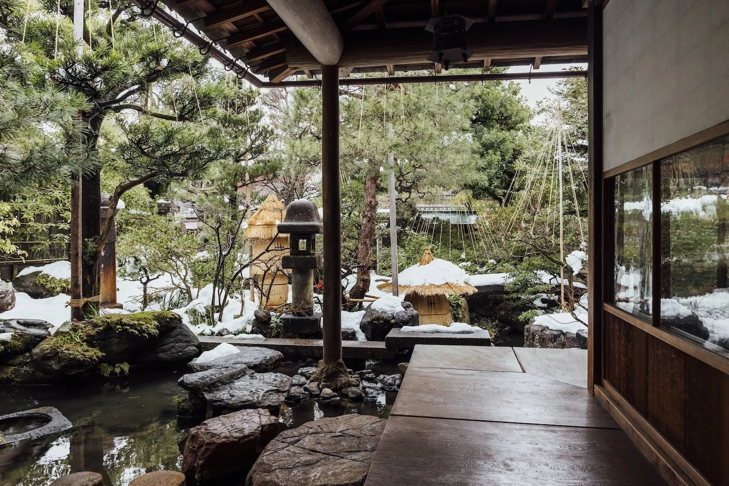 Snow dusts the pine trees and stone lanterns of a traditional Japanese garden