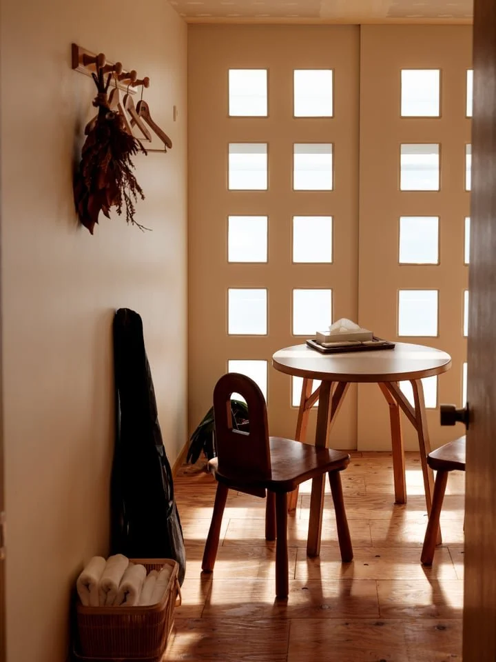 A wooden table is illuminated by natural sunlight in a simple, cream-hued guest room in Himi, Toyama