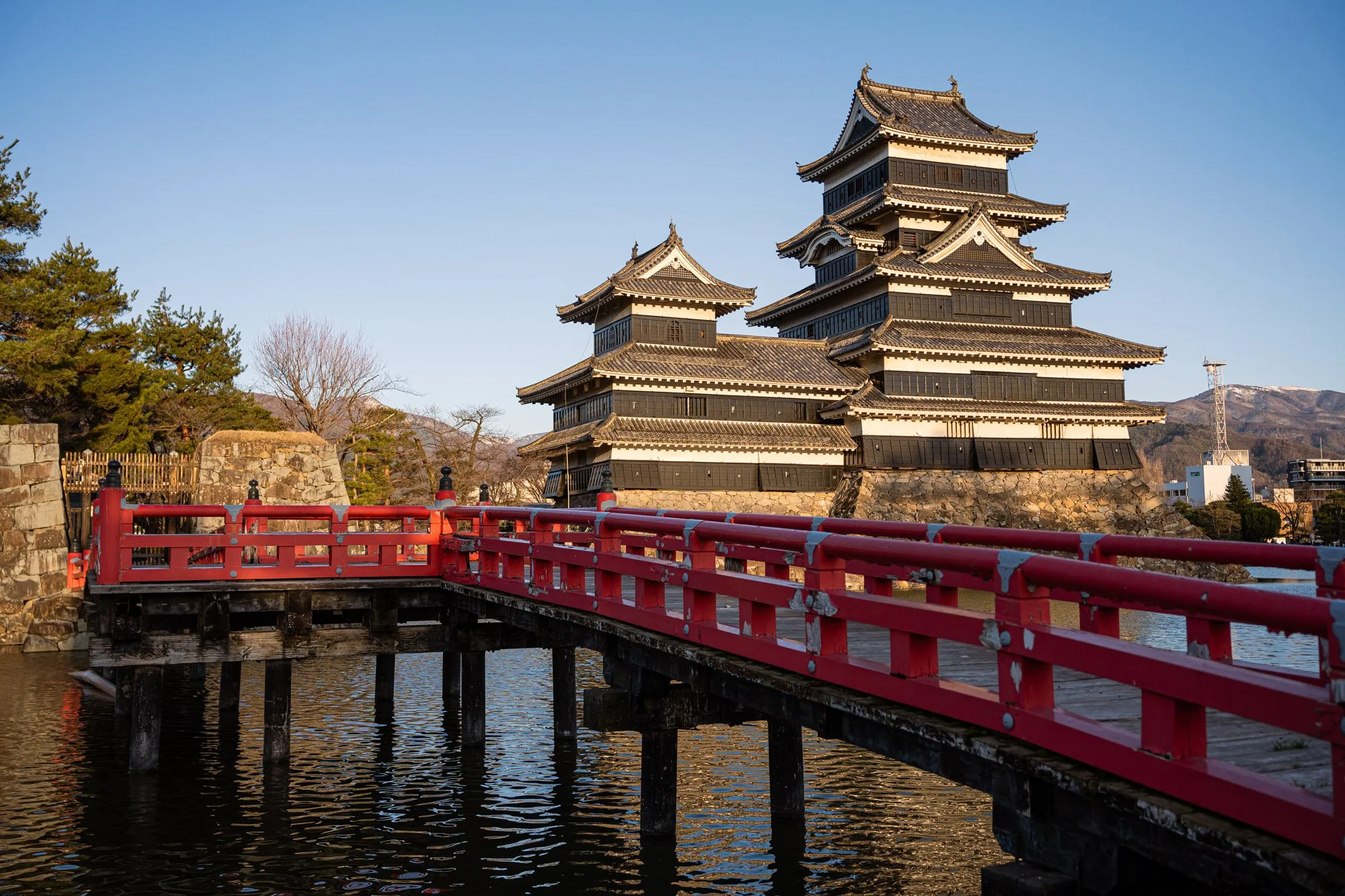 A Japanese castle looms large across a red wooden bridge