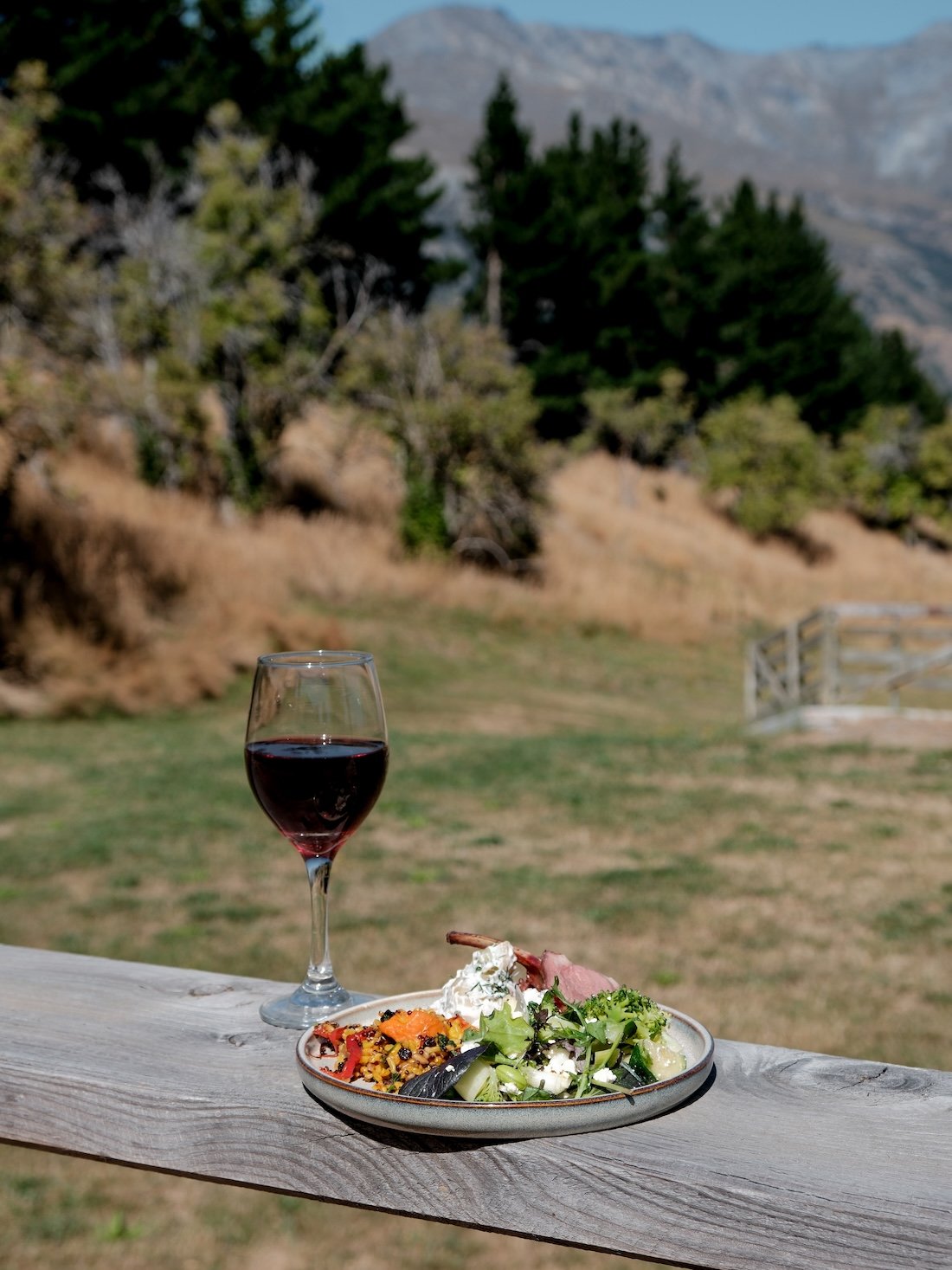 A picnic lunch rests on a wooden fence