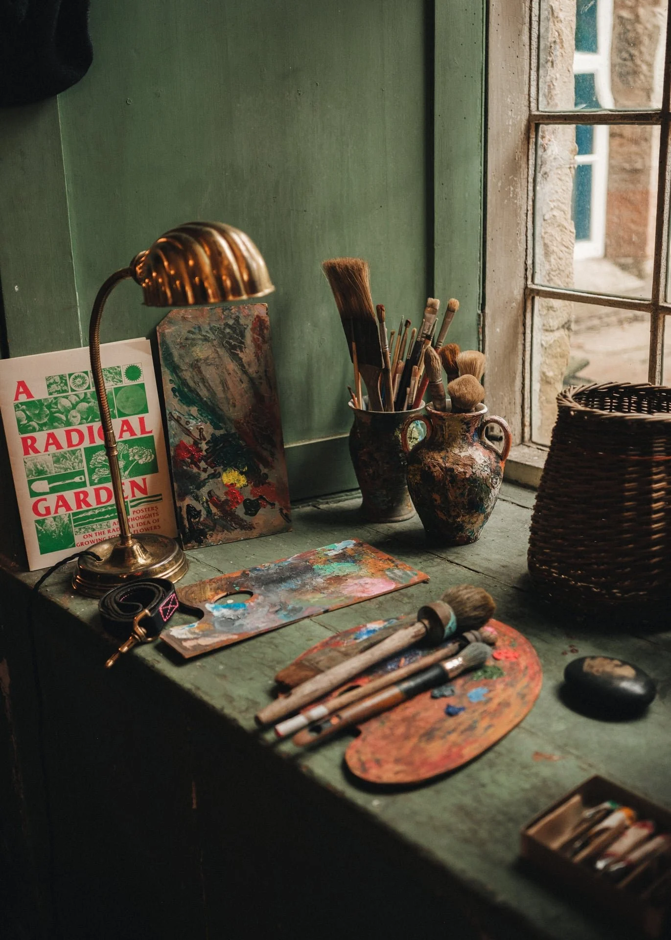 paints and an artists' palette sit by a sunlit window