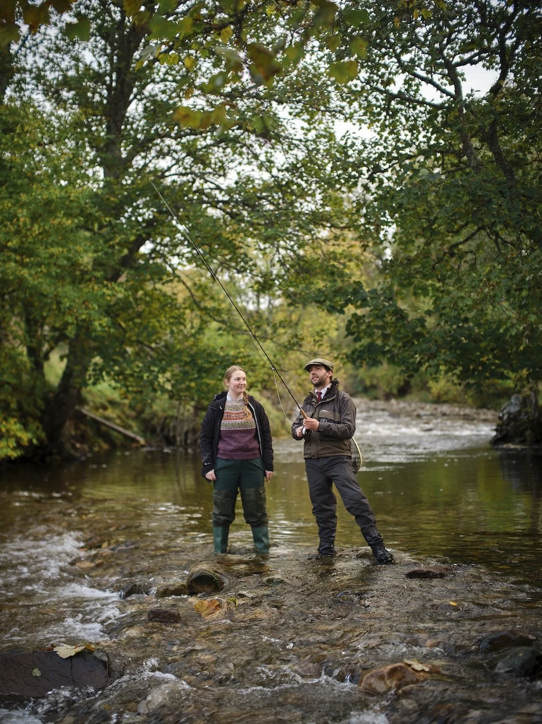 A man and woman fly fish is a fast moving Scottish river
