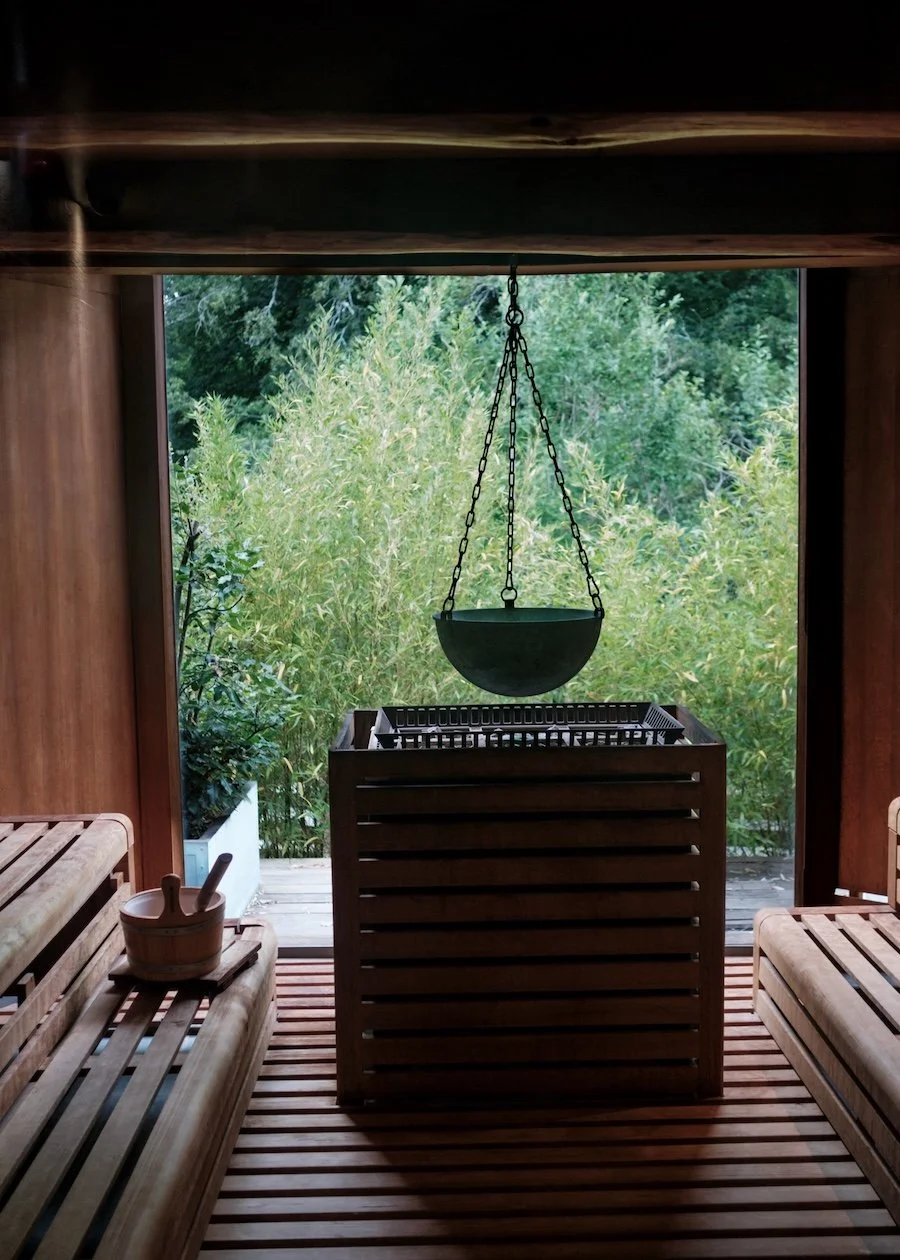 Inside a wooden sauna. Above the coals, a metal bowl is suspected from the beams, which scents the air