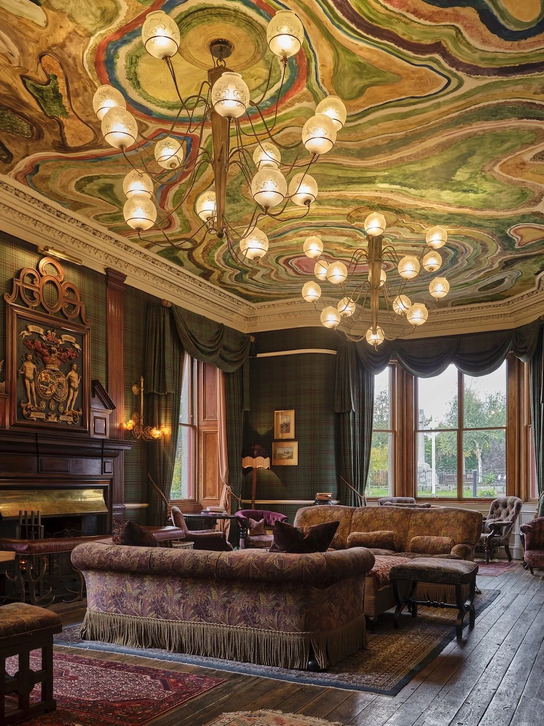 The hand-painted ceiling of the drawing room in The Fife Arms hotel in Cairngorms - the swirling pattern a contrast to the wooden fireplace and traditional Scottish decor.
