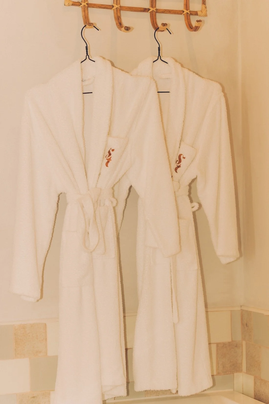 True fluffy white robes hang in a hotel bedroom