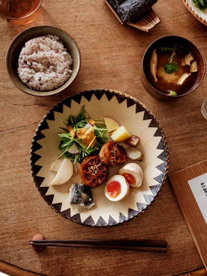 A bowel of vegetables, rice and miso on a wooden table in the sun at HOUSEHOLD in Himi, Toyama