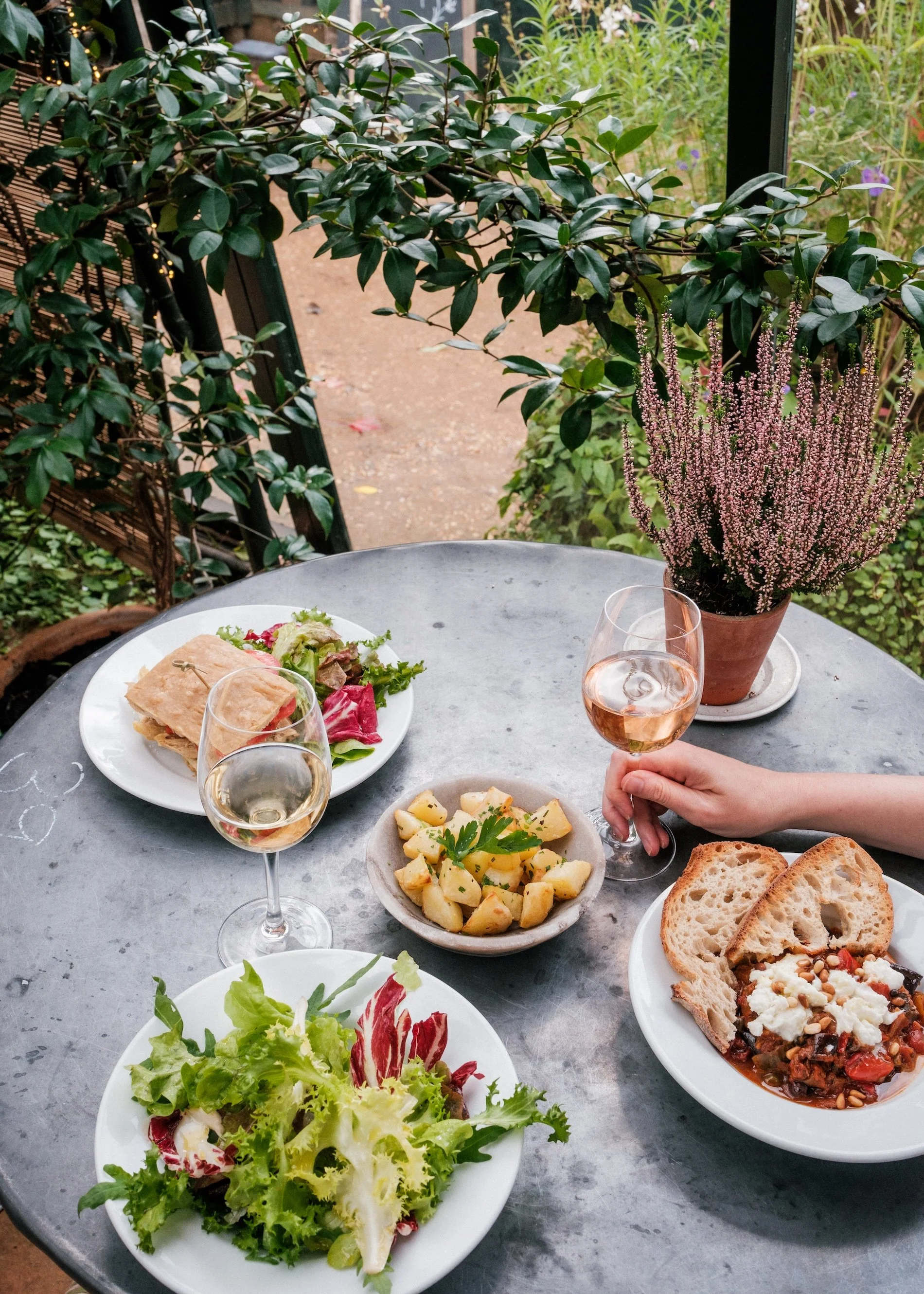A series of vegetable dishes sit on a greenery-surrounded table at Petersham Nurseries, London