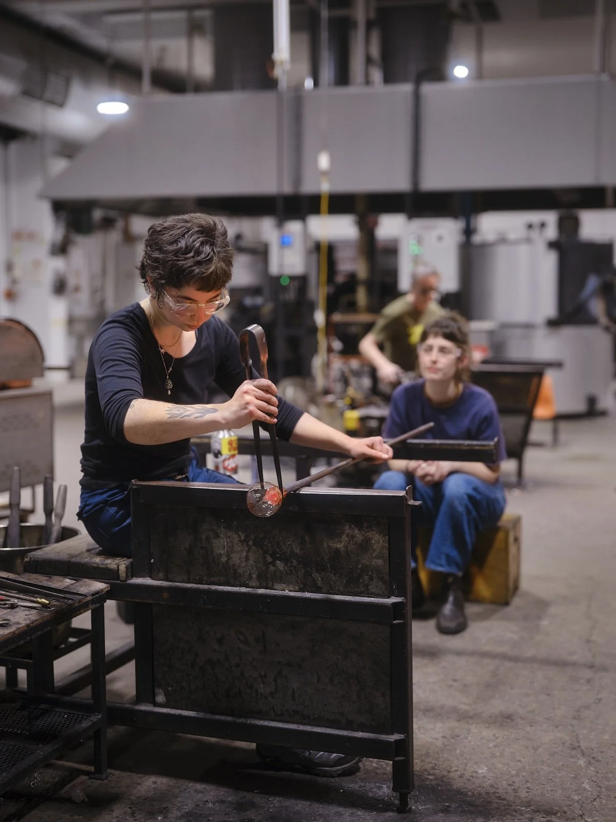 Two glass artists work together on a small glass sculpture