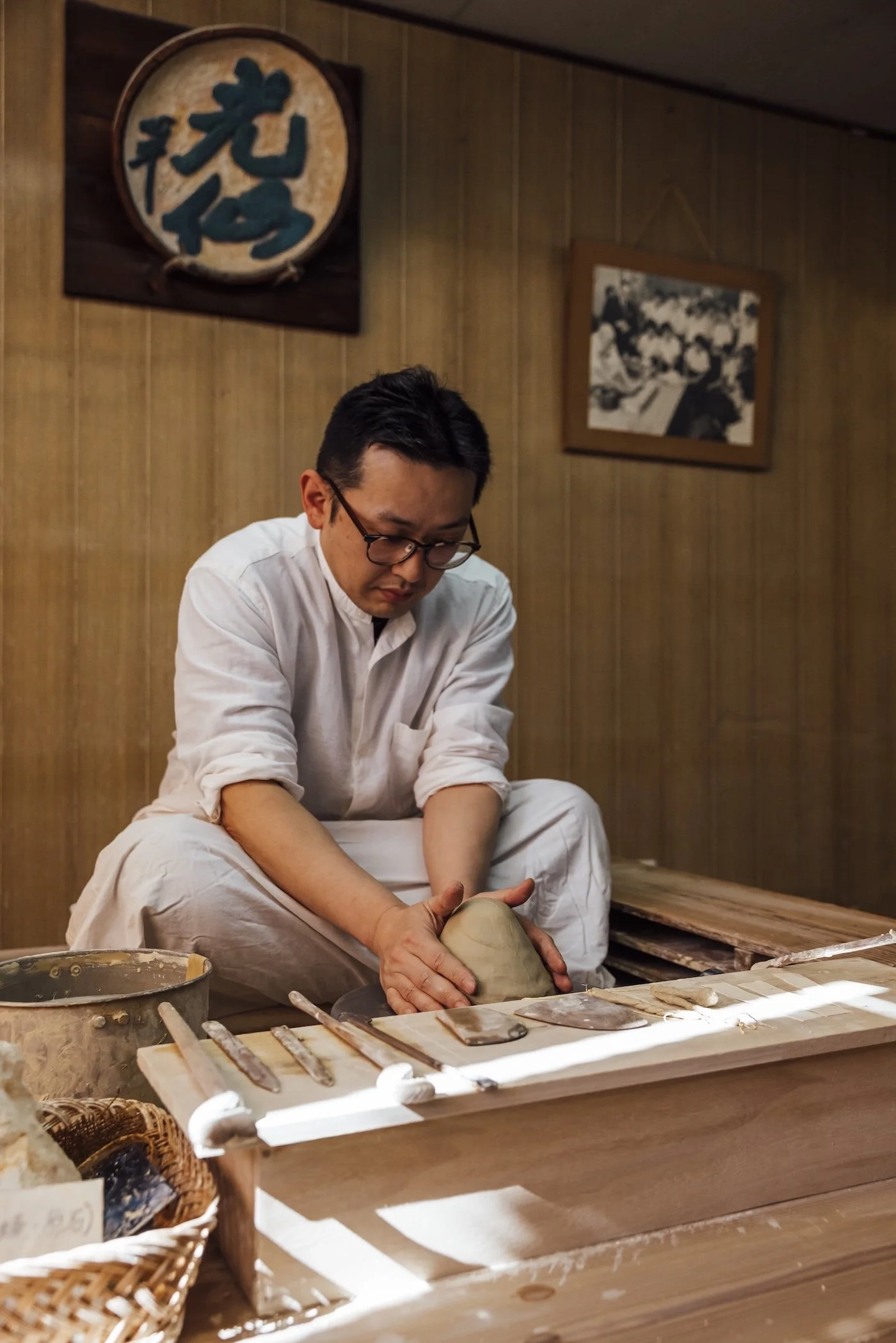 An artisan works at a potters wheel, turning clay into a small vase
