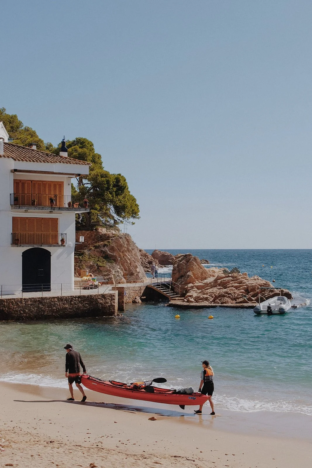 Two men carry a red canoe away from the water