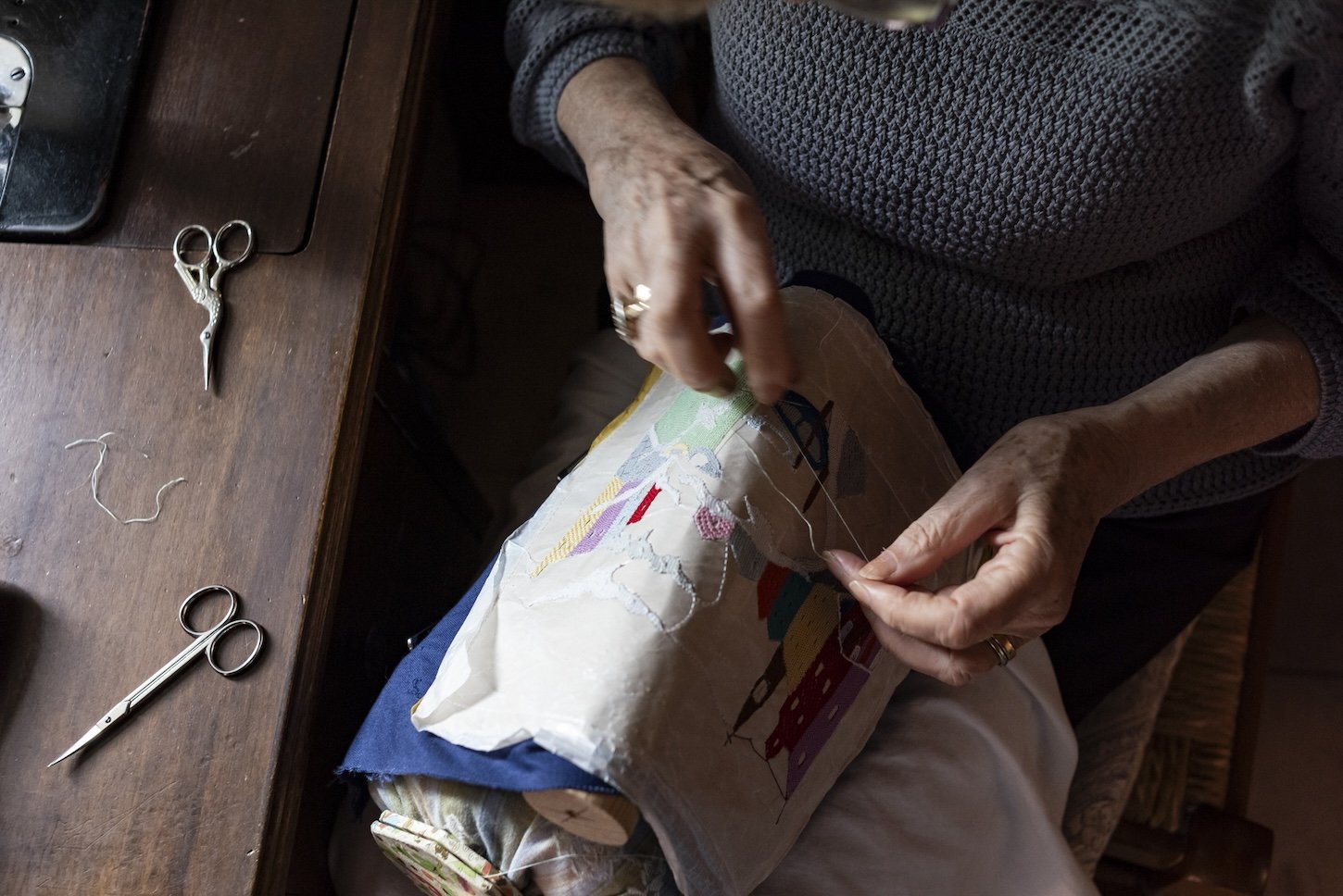 A close up of artist Sandra Mavaracchio's hand as she embroiders cloth with a scene from Venice