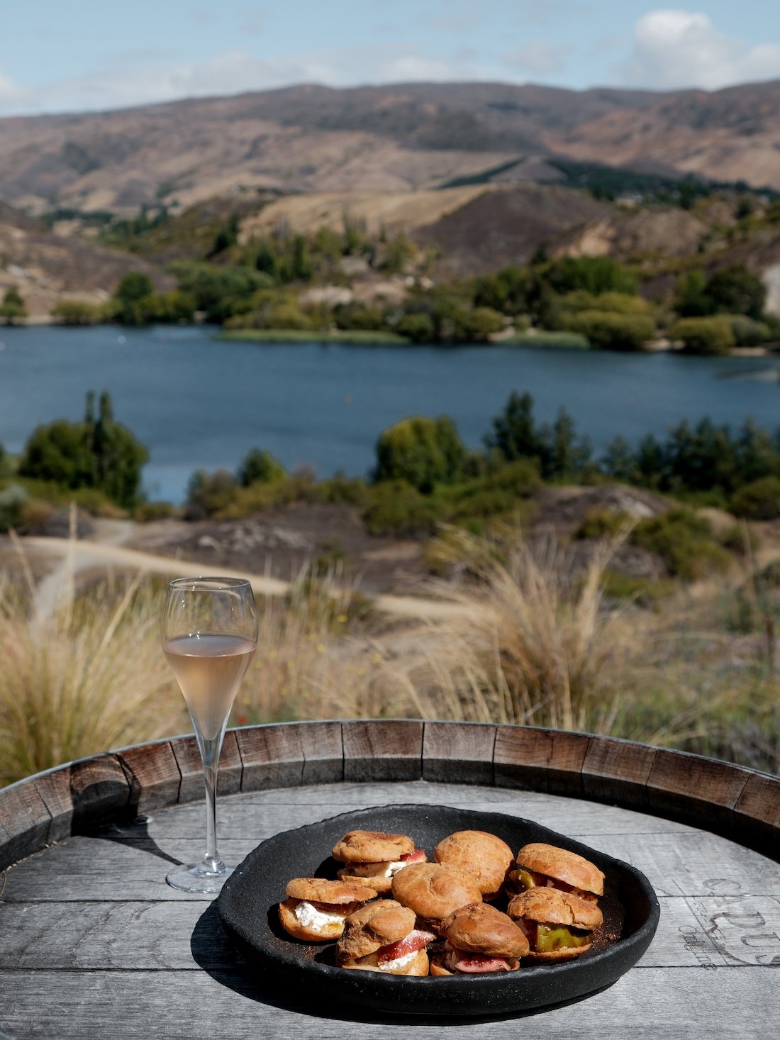 sparkling wine and a ceramic plate filled with canapés rests on a wooden barrel