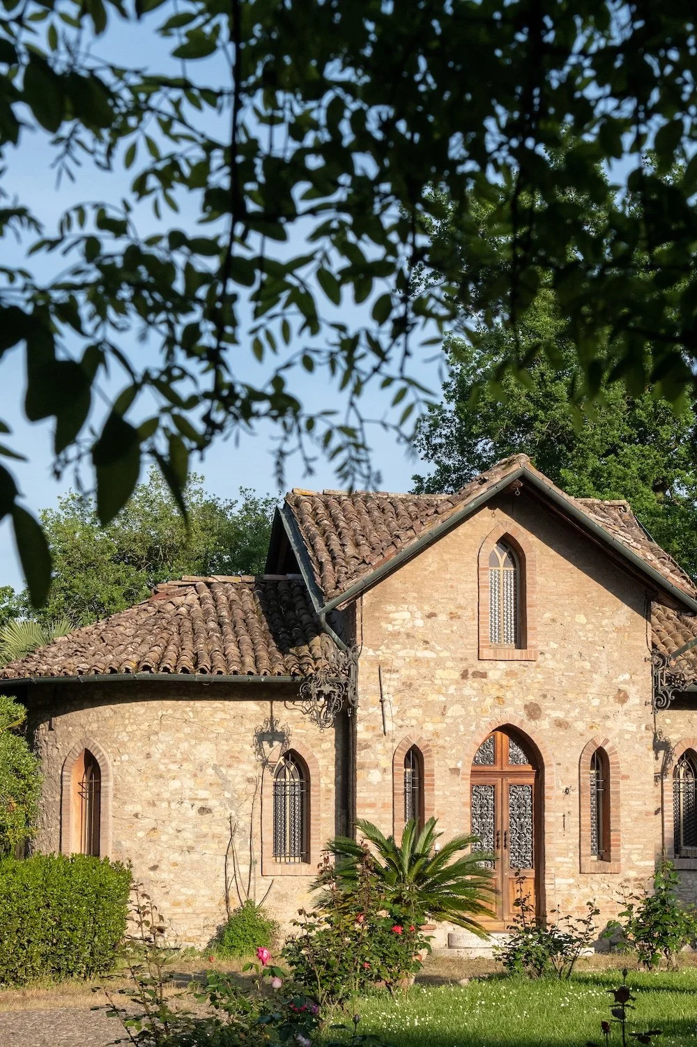 A stone chapels stands in the palm-dotted garden of  Il Borgo del Balsamico, a guest house in Emilia-Romagna