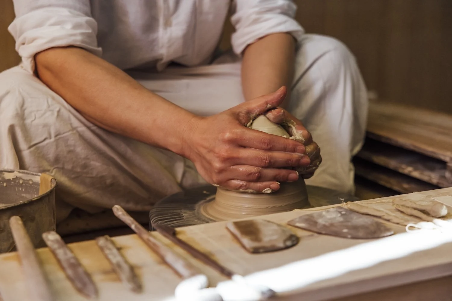 A close up of a potters hands as he starts to shape a lump of clay