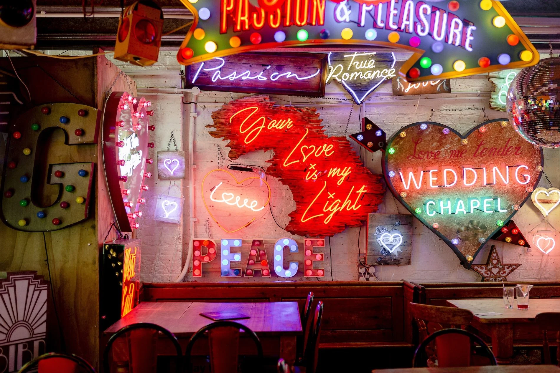 A mass of neon signs line an exposed brick wall