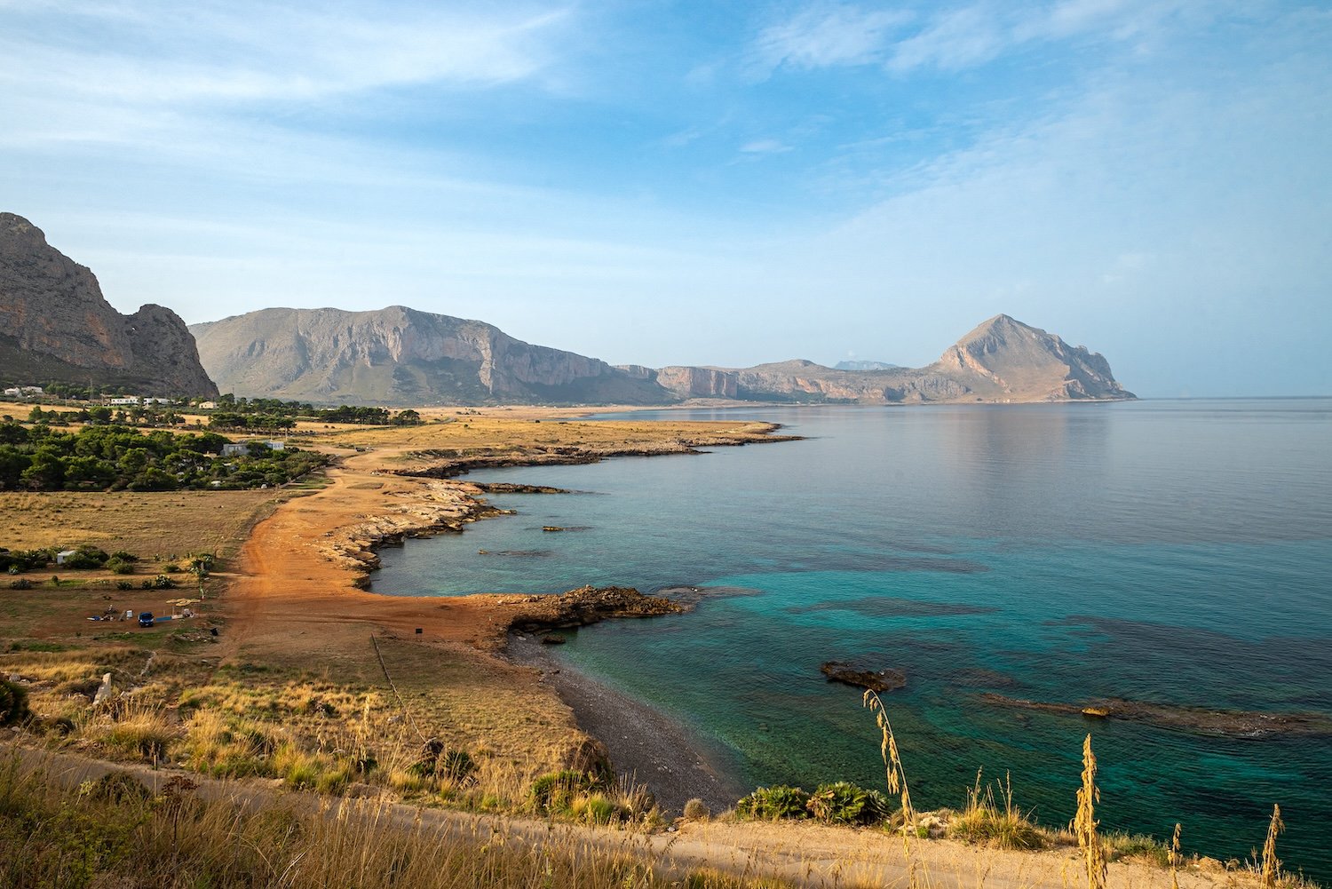 A rugged, mountainous coastline meets turquoise water