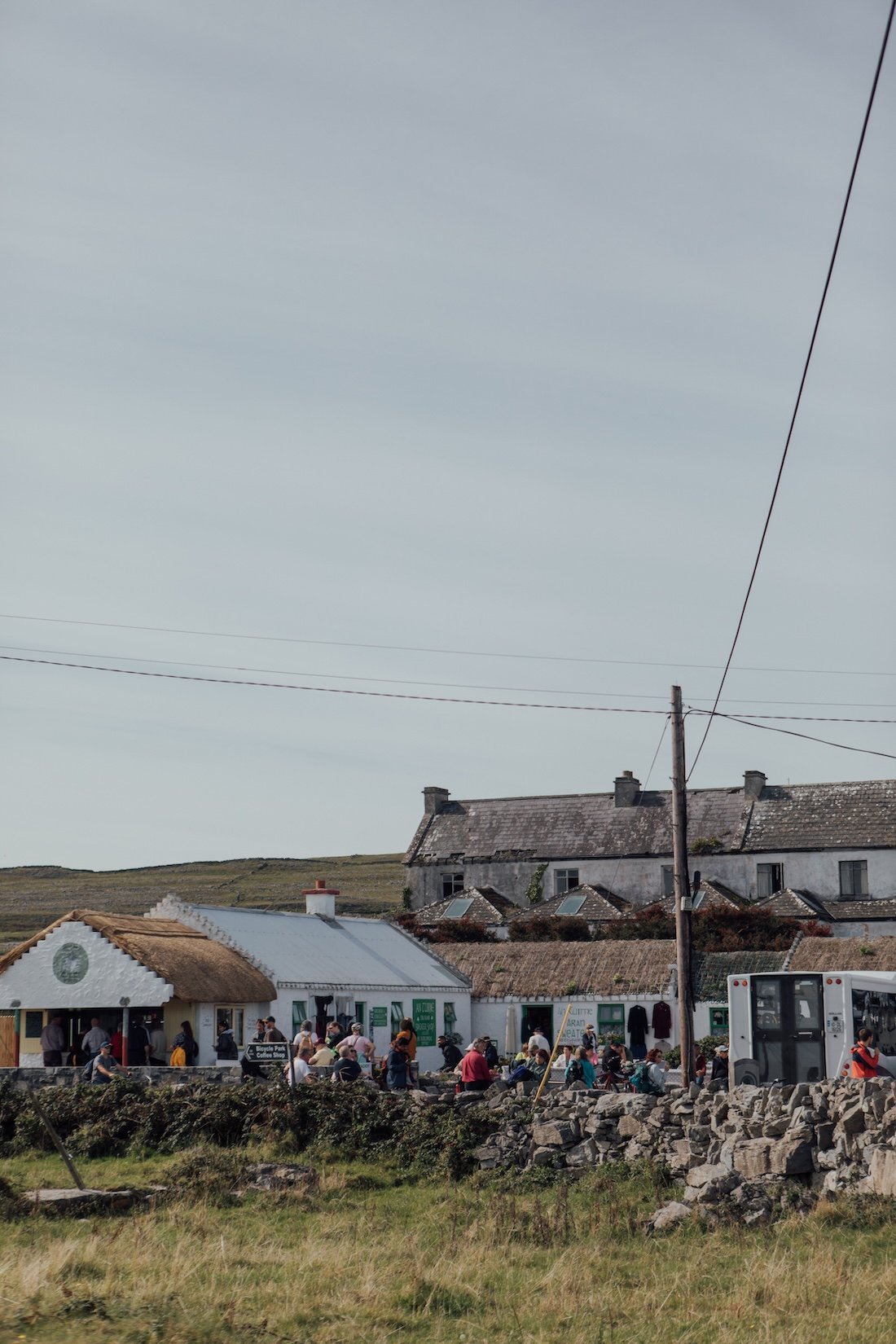 Locals settle on the stone wall outside a whitewashed Irish country pub