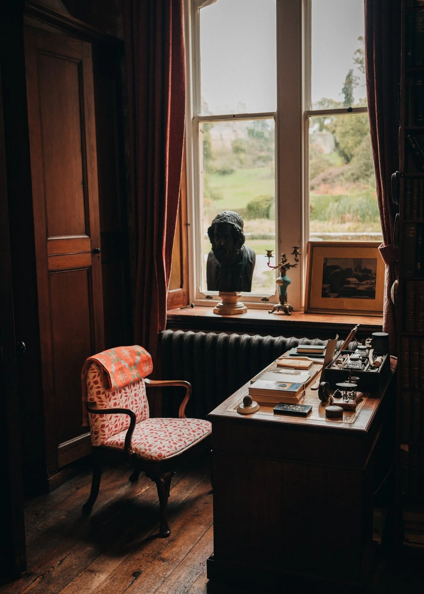 A desk, filled with pages and antiques, is bathed in natural light
