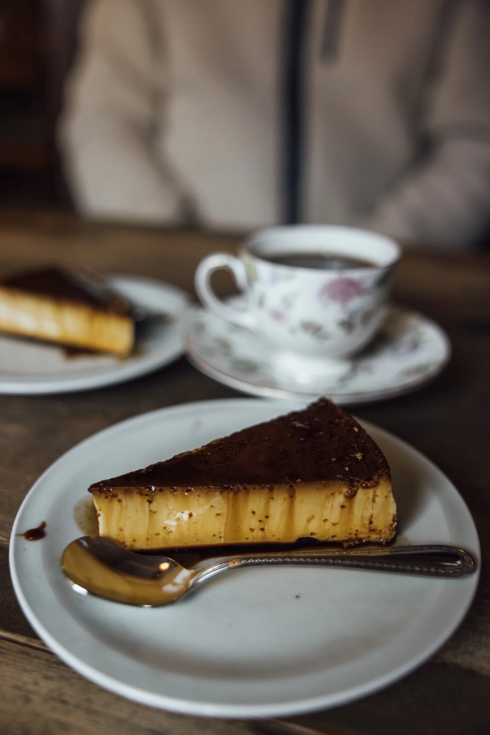 A slice of flan and a cup of coffee on a wooden table in a Kanazawa coffee shop