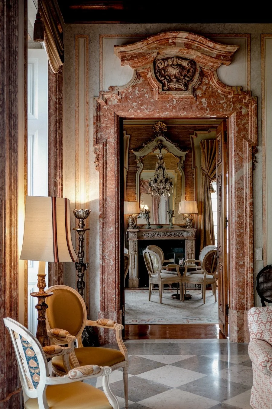 A marble doorway leads to an ornate bar, decorated with chandeliers and antique furniture