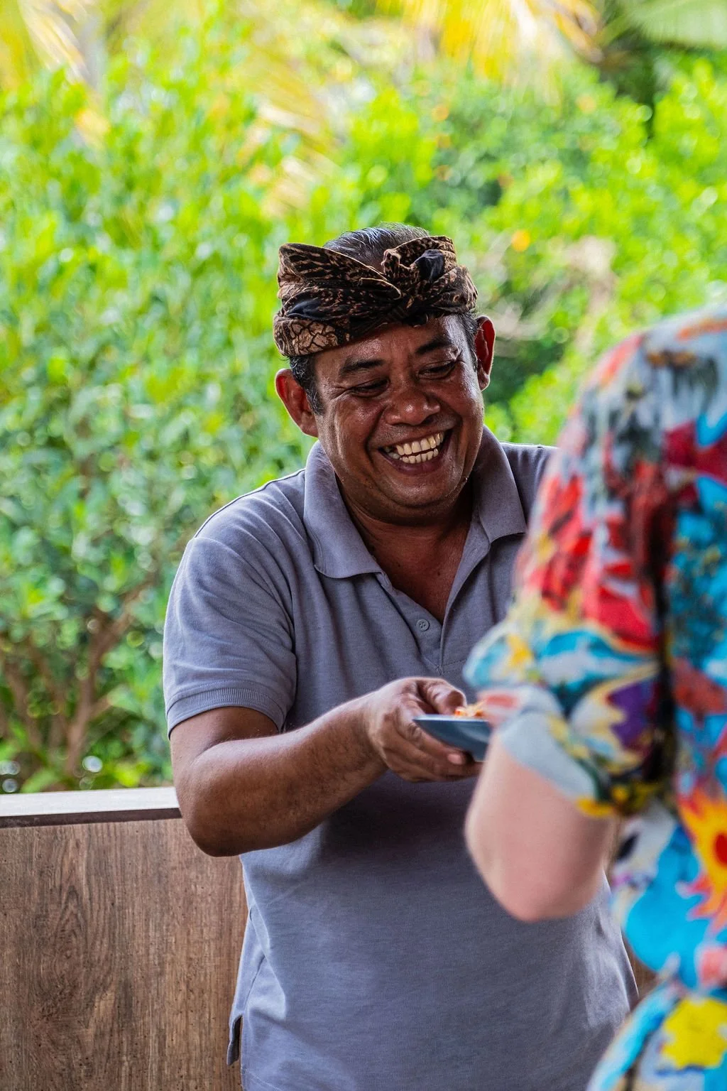 A smiling man serves a guest a bowl of food in Ubud Bali