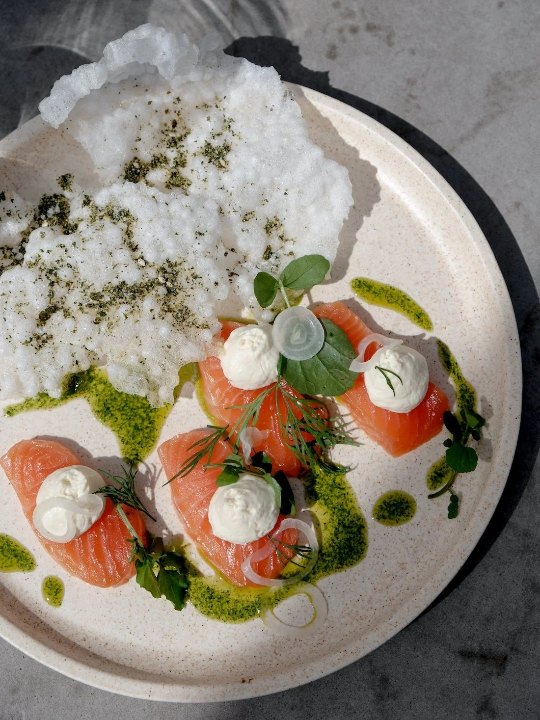 A close up of a dish featuring smoked salmon, basil, and olive drizzle