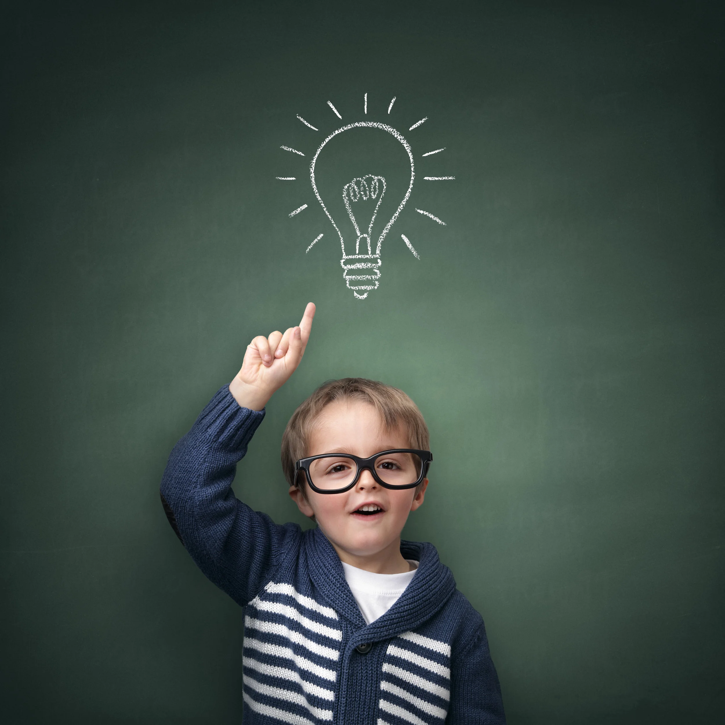 Schoolboy standing in front of a blackboard with a bright idea light bulb above his head concept for.jpg