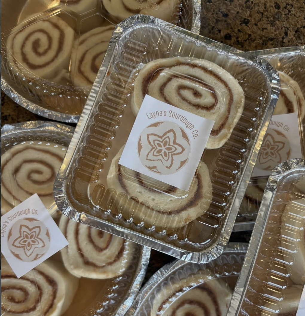 Pre-packaged cinnamon rolls with a spiral shape in aluminum trays labeled with 'Layne's Sourdough Co.'