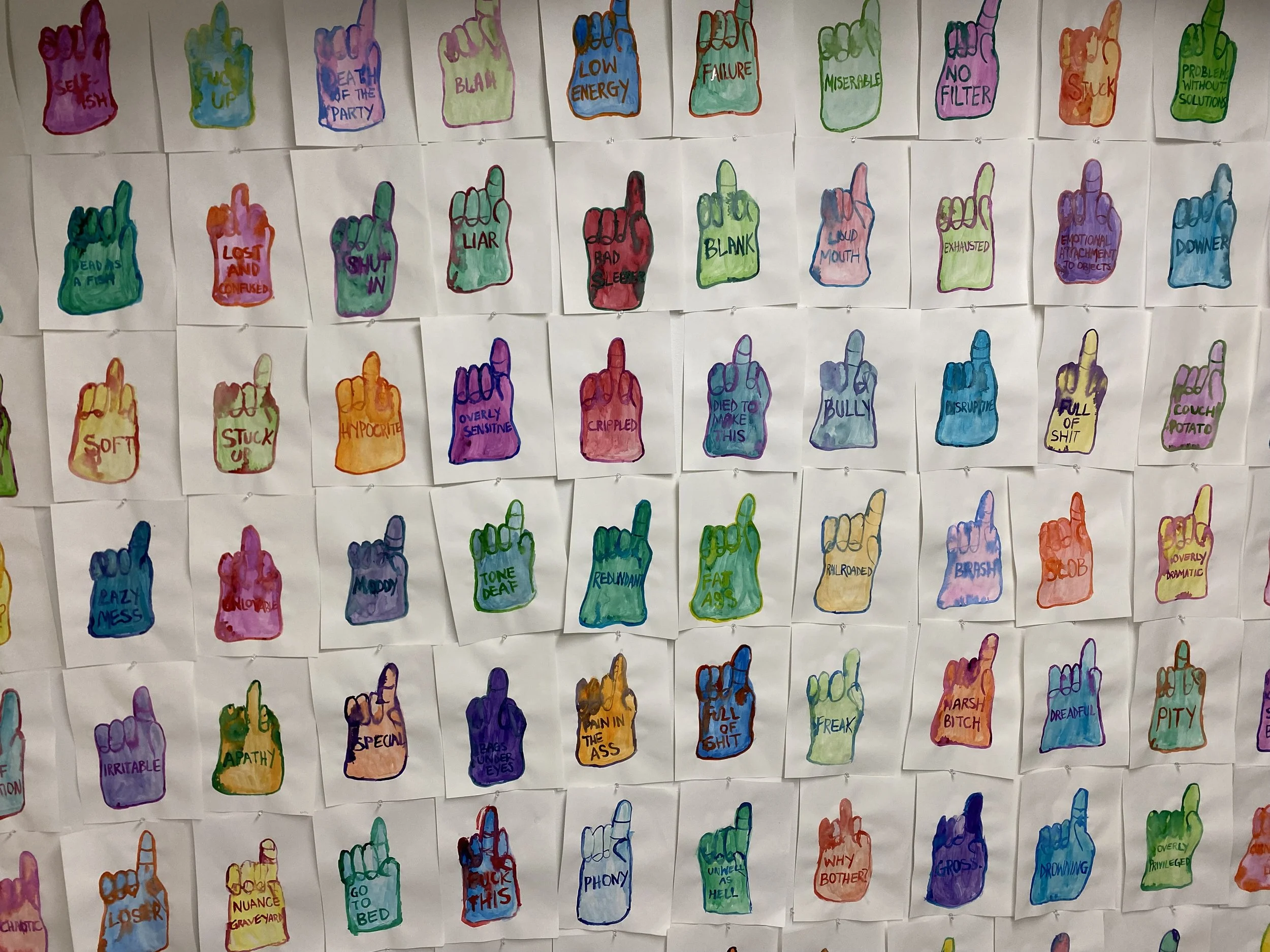   A detail shot of a wall covered in a grid of nine inch by twelve inch bright and colorful watercolor drawings on white paper. The drawings continue beyond the image making it seem like they have wallpapered the entire world. The sketches are of foa